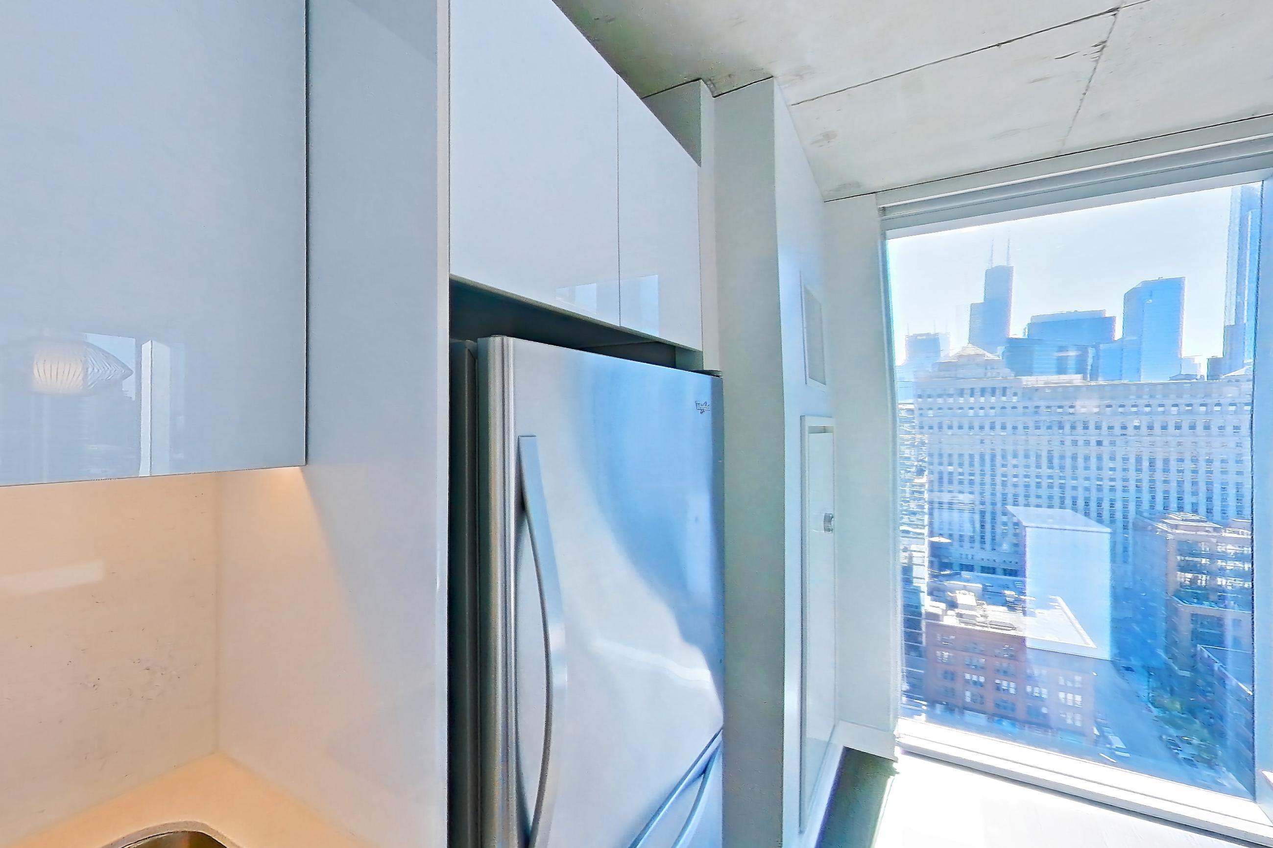 Kitchen with black appliances, cooktop, dark wood-finish flooring, electric cooktop, light stone countertops, light wood-finish flooring, oven/range, refrigerator, skyline view, and stainless steel appliances, Apartment 2302 at 220 WIL