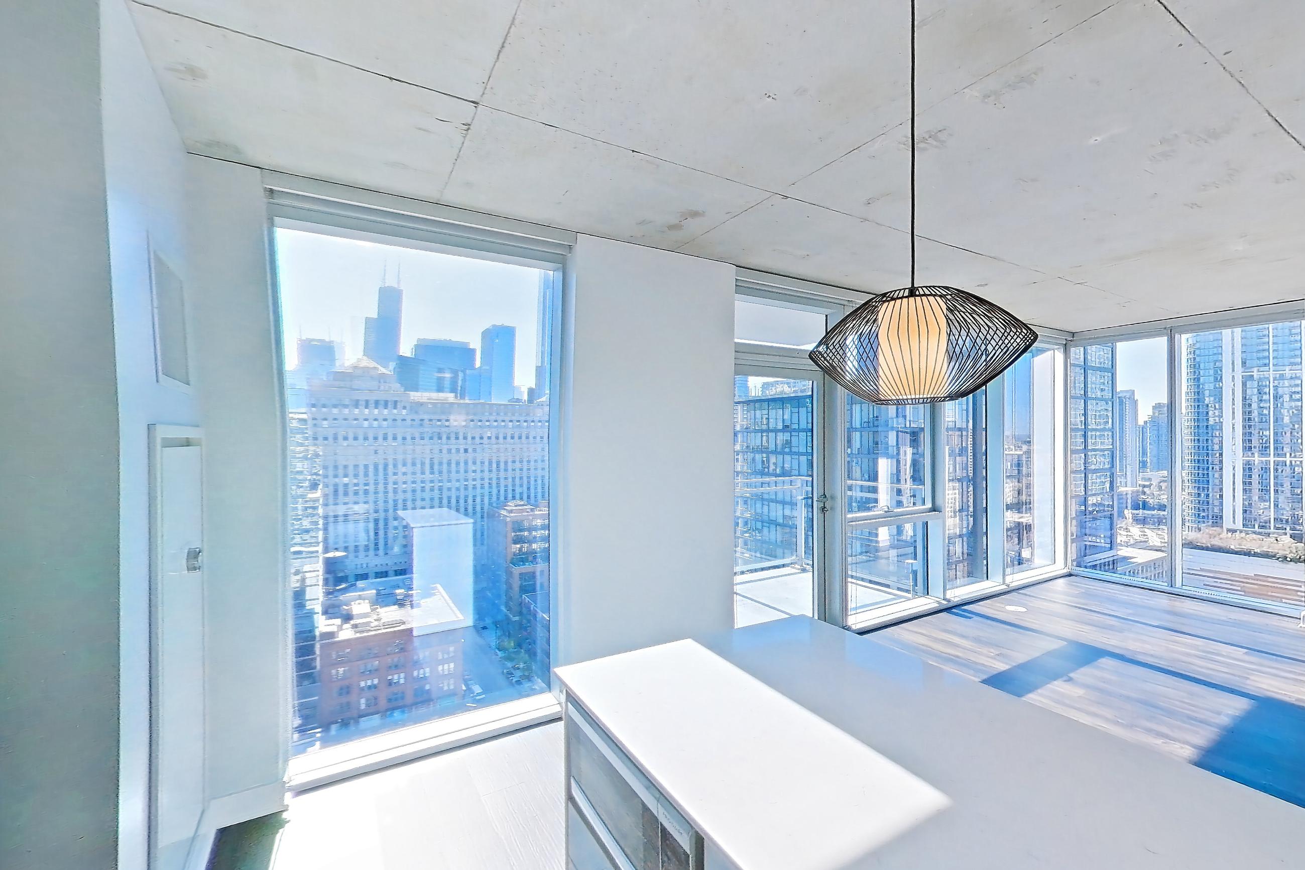 Kitchen with black appliances, cooktop, dark wood-finish flooring, electric cooktop, light stone countertops, light wood-finish flooring, oven/range, refrigerator, skyline view, and stainless steel appliances, Apartment 2302 at 220 WIL
