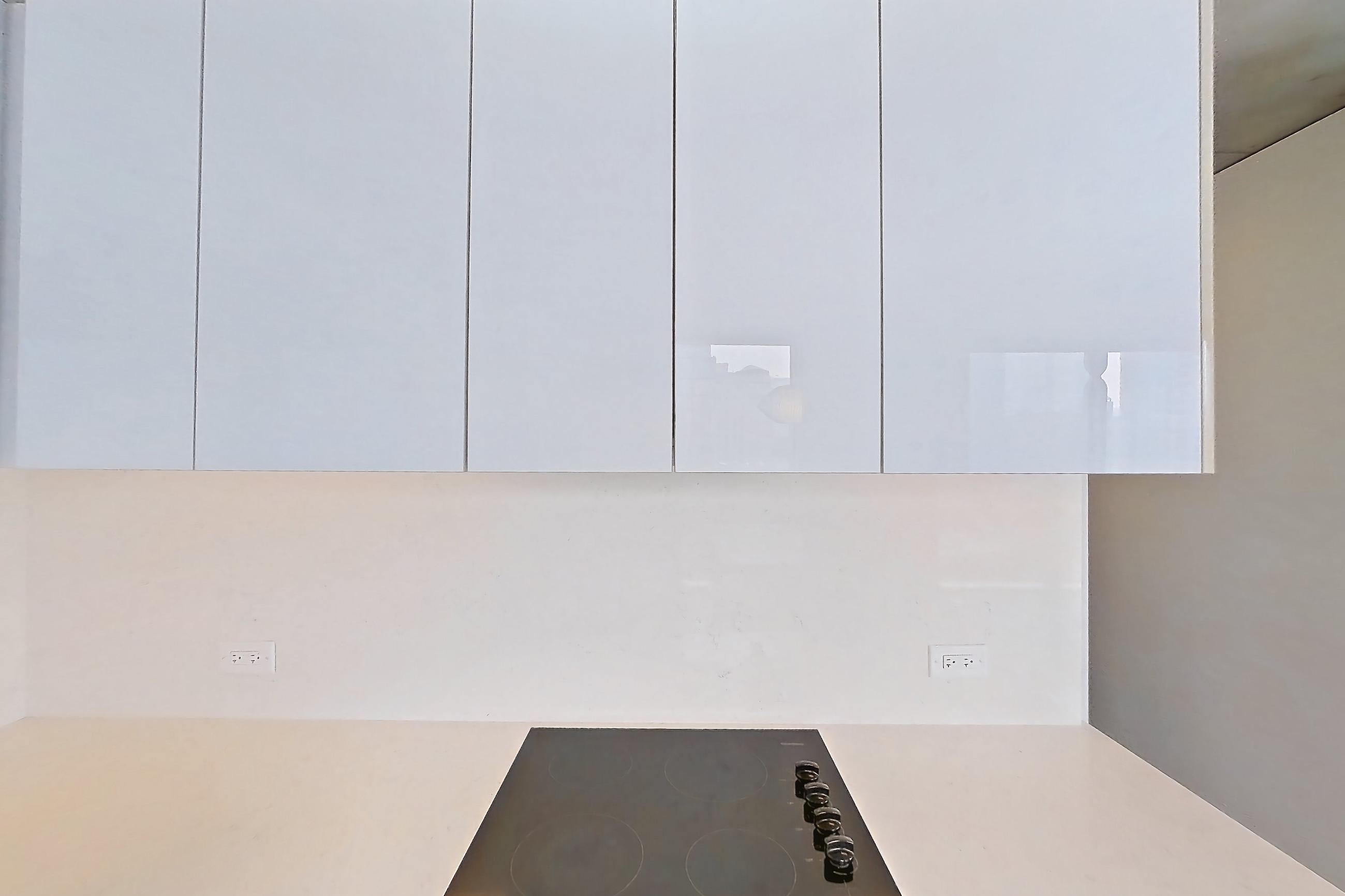 Kitchen with black appliances, cooktop, dark wood-finish flooring, electric cooktop, light stone countertops, oven/range, and stainless steel appliances, Apartment 1610 at 220 WIL