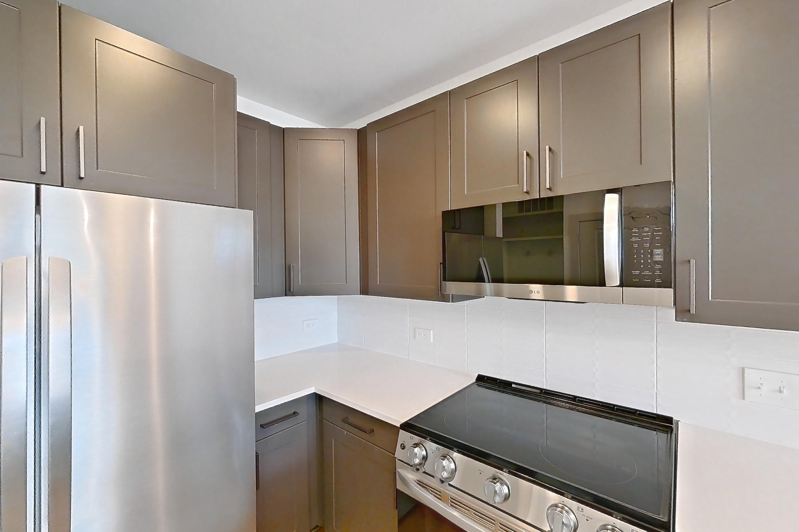 Kitchen with cooktop, electric cooktop, electric range, light countertops, light stone countertops, light wood-finish flooring, oven/range, refrigerator, stainless steel appliances, and water & ice dispenser, Apartment 2247 at Groves South Congress