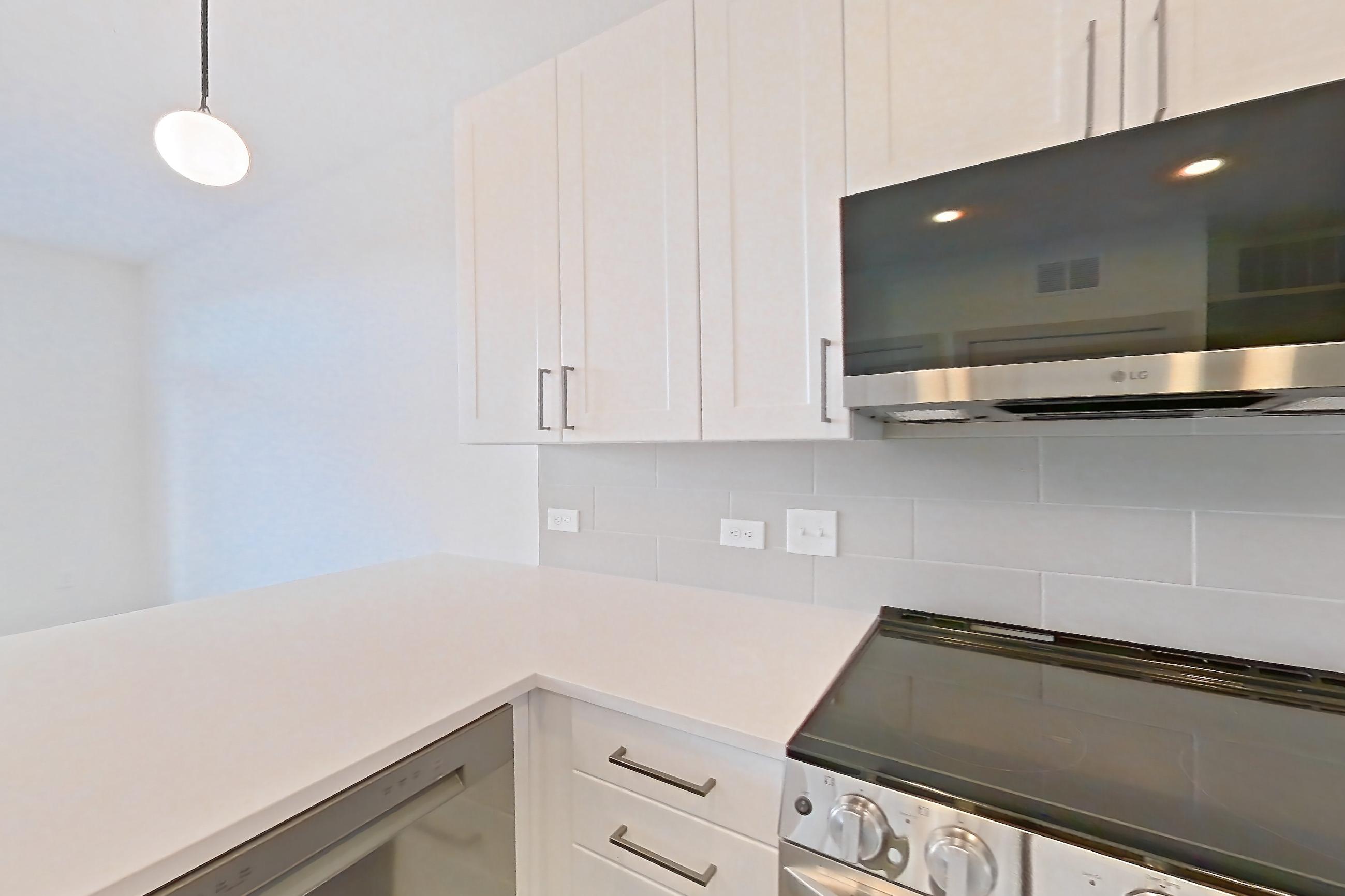 Kitchen with dark wood-finish flooring, dishwasher, electric range, light countertops, light stone countertops, light wood-finish flooring, oven/range, and stainless steel appliances, Apartment 2346 at Groves South Congress