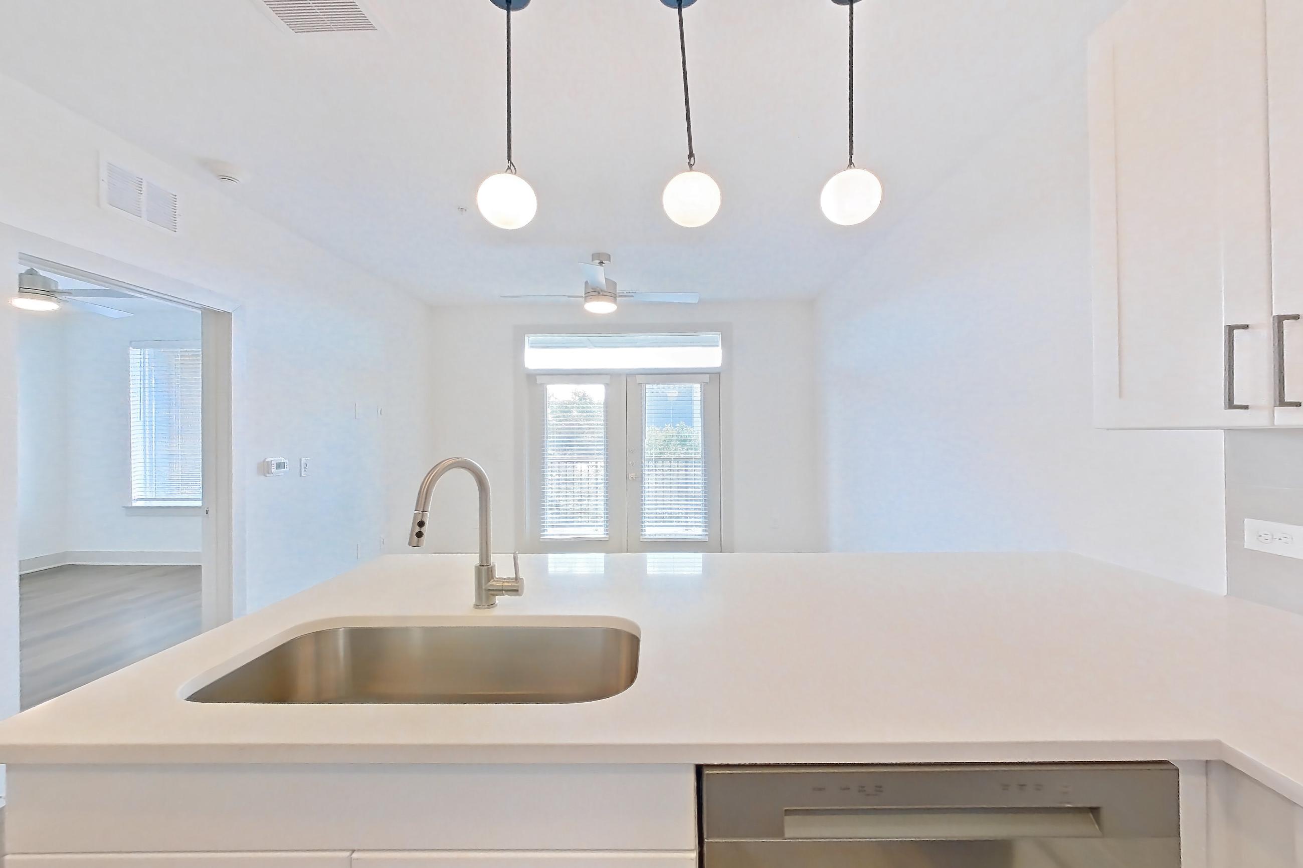 Kitchen with dark wood-finish flooring, dishwasher, electric range, light countertops, light stone countertops, light wood-finish flooring, oven/range, and stainless steel appliances, Apartment 2346 at Groves South Congress