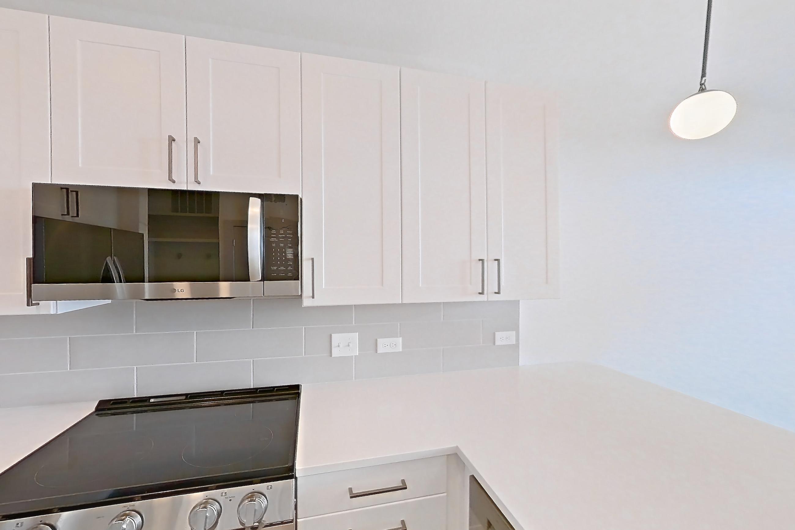 Kitchen with dishwasher, electric range, light countertops, light wood-finish flooring, oven/range, refrigerator, stainless steel appliances, and water & ice dispenser, Apartment 2347 at Groves South Congress