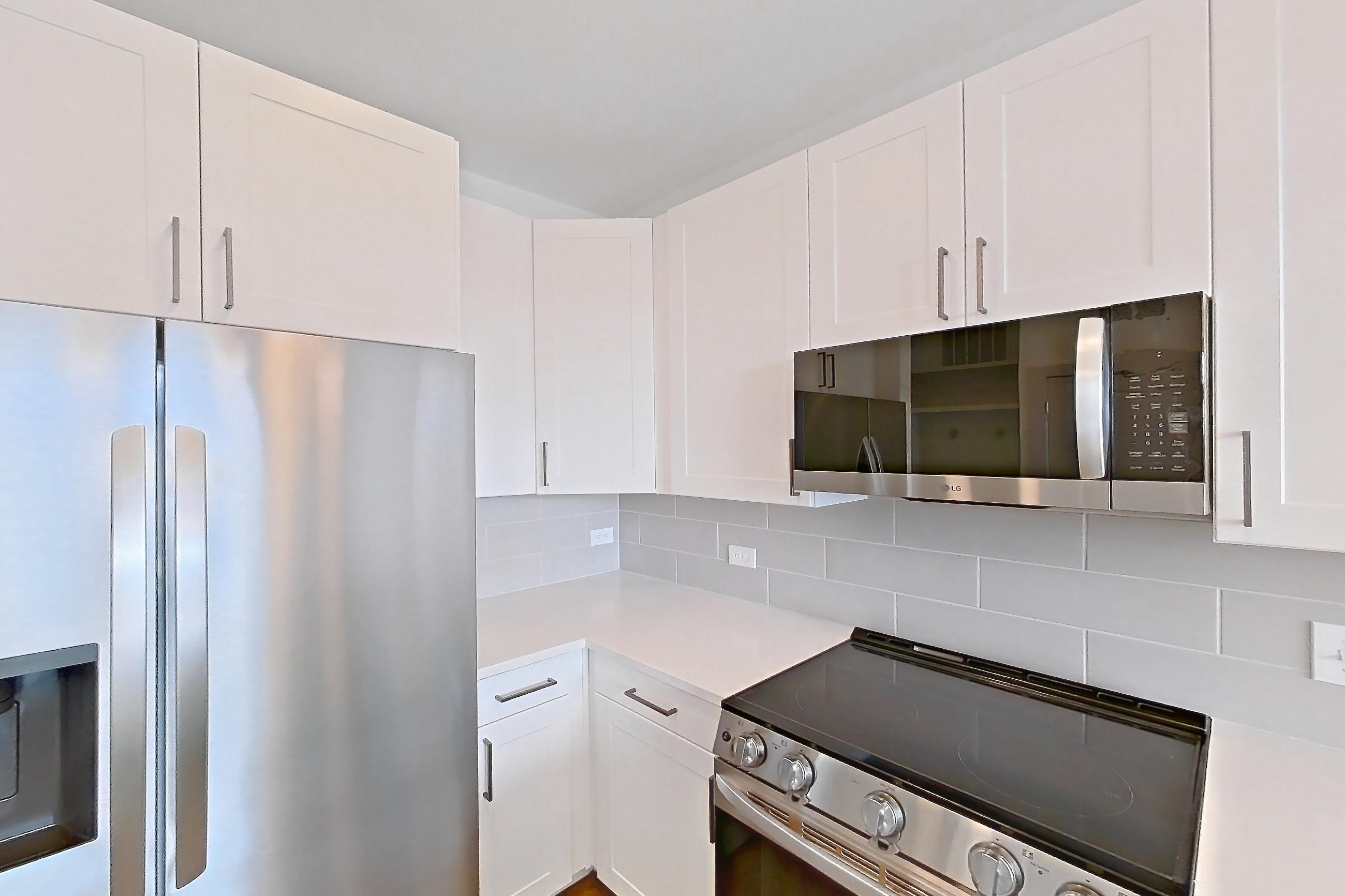 Kitchen with dishwasher, electric range, light countertops, light wood-finish flooring, oven/range, refrigerator, stainless steel appliances, and water & ice dispenser, Apartment 2347 at Groves South Congress