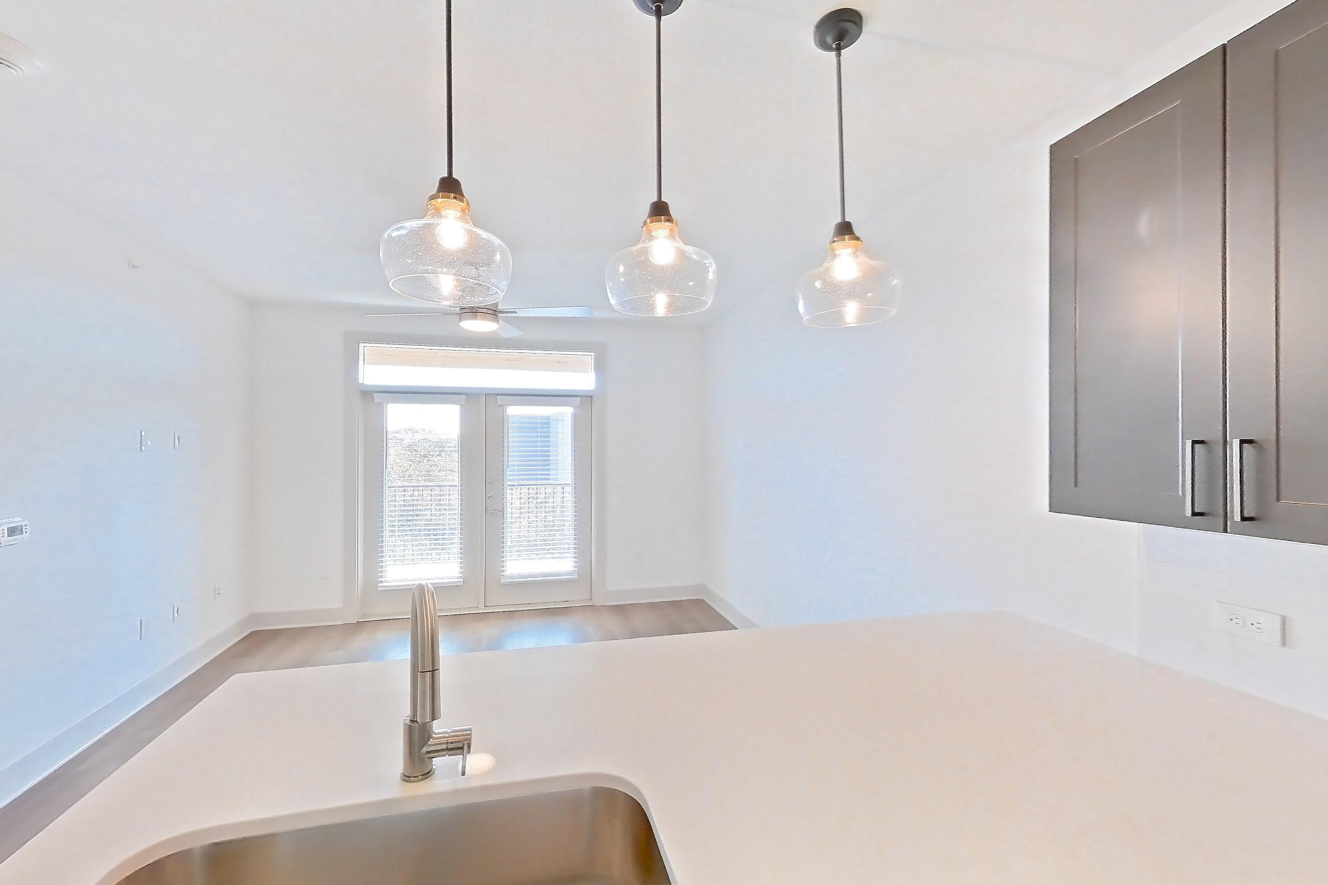 Kitchen with dishwasher, electric range, light countertops, light wood-finish flooring, microwave, oven/range, refrigerator, stainless steel appliances, and water & ice dispenser, Apartment 2446 at Groves South Congress