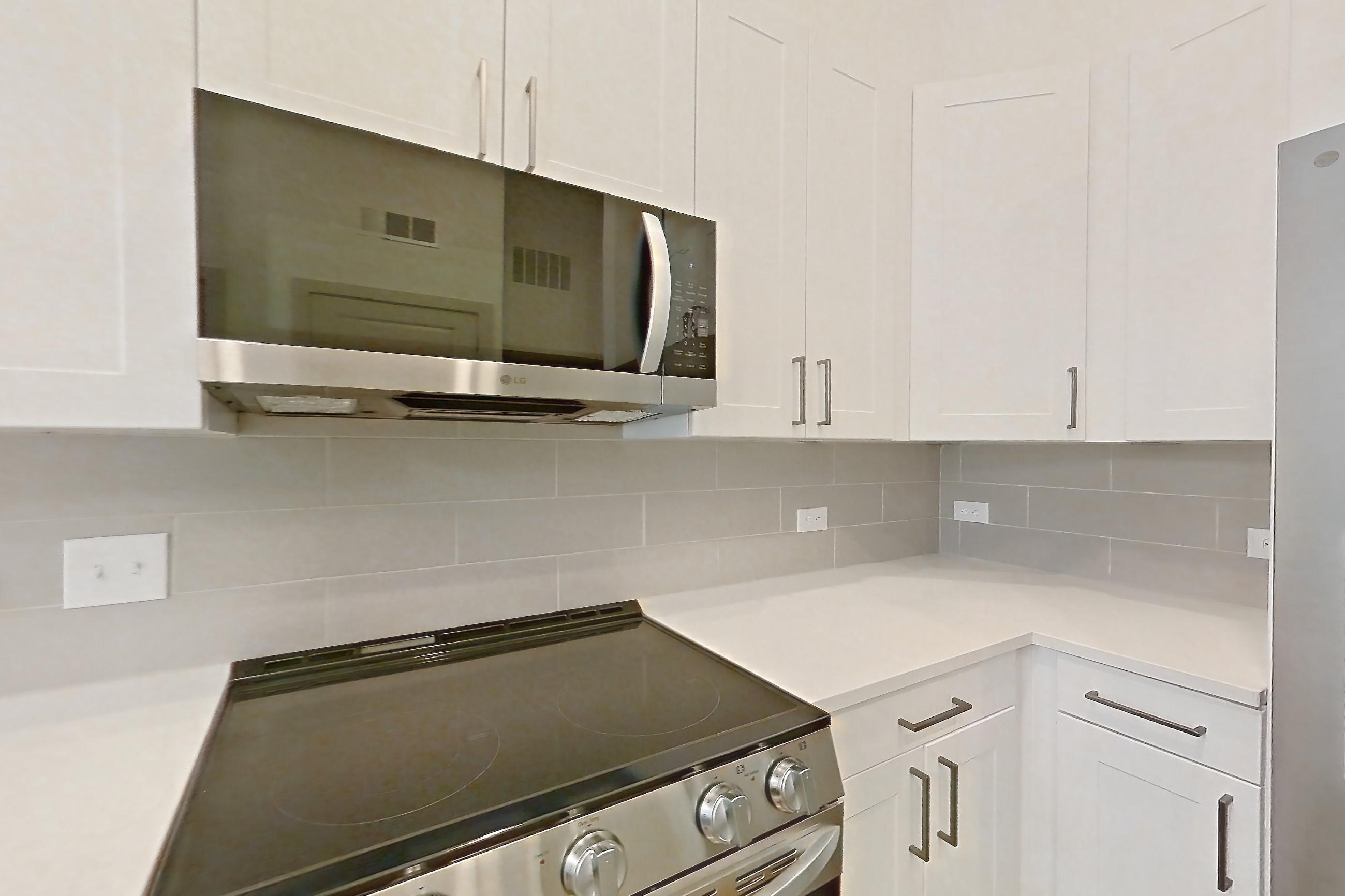 Kitchen with dishwasher, electric range, light countertops, light stone countertops, light wood-finish flooring, microwave, oven/range, and stainless steel appliances, Apartment 2144 at Groves South Congress