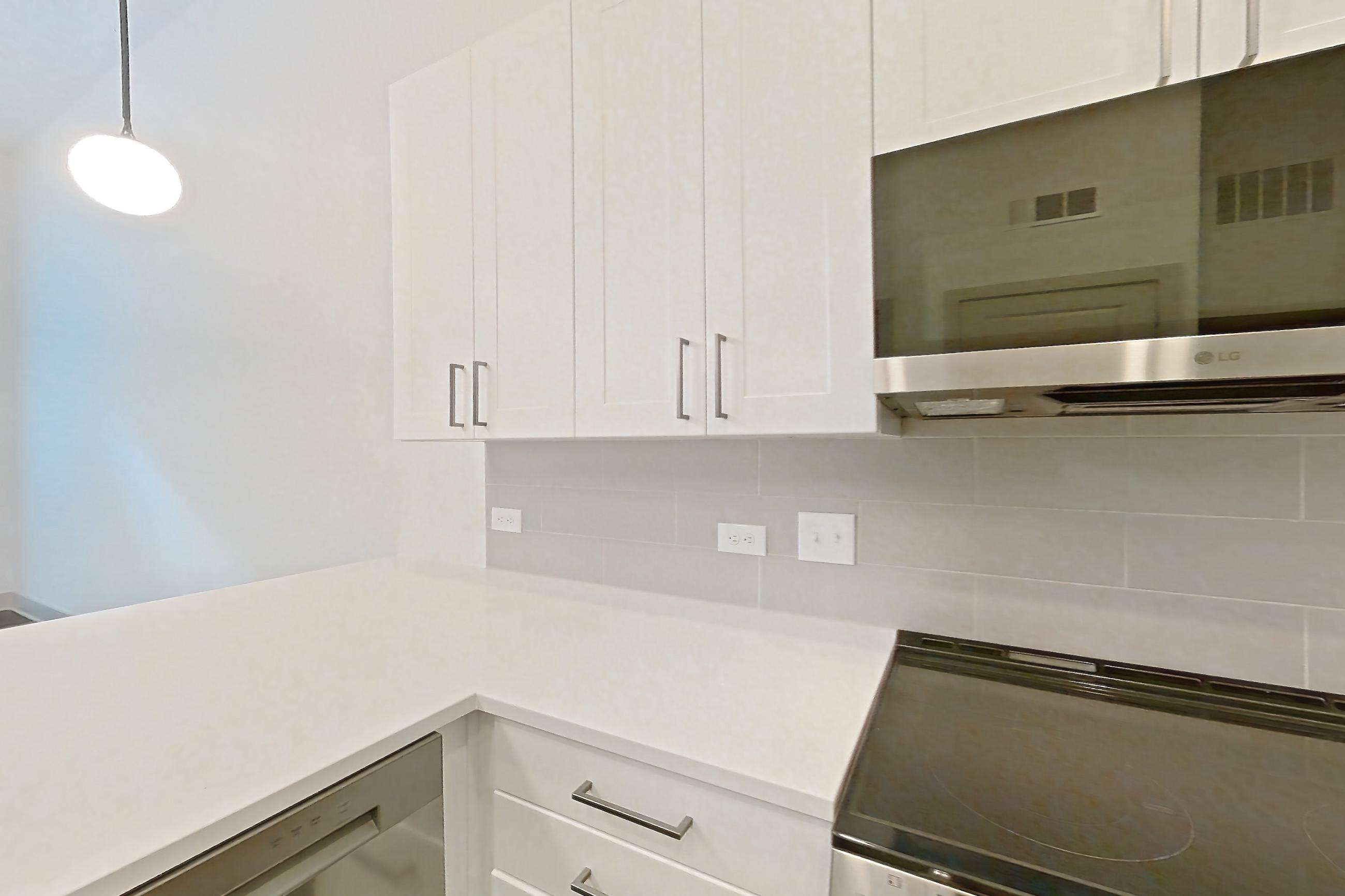 Kitchen with dishwasher, electric range, light countertops, light stone countertops, light wood-finish flooring, microwave, oven/range, and stainless steel appliances, Apartment 2144 at Groves South Congress