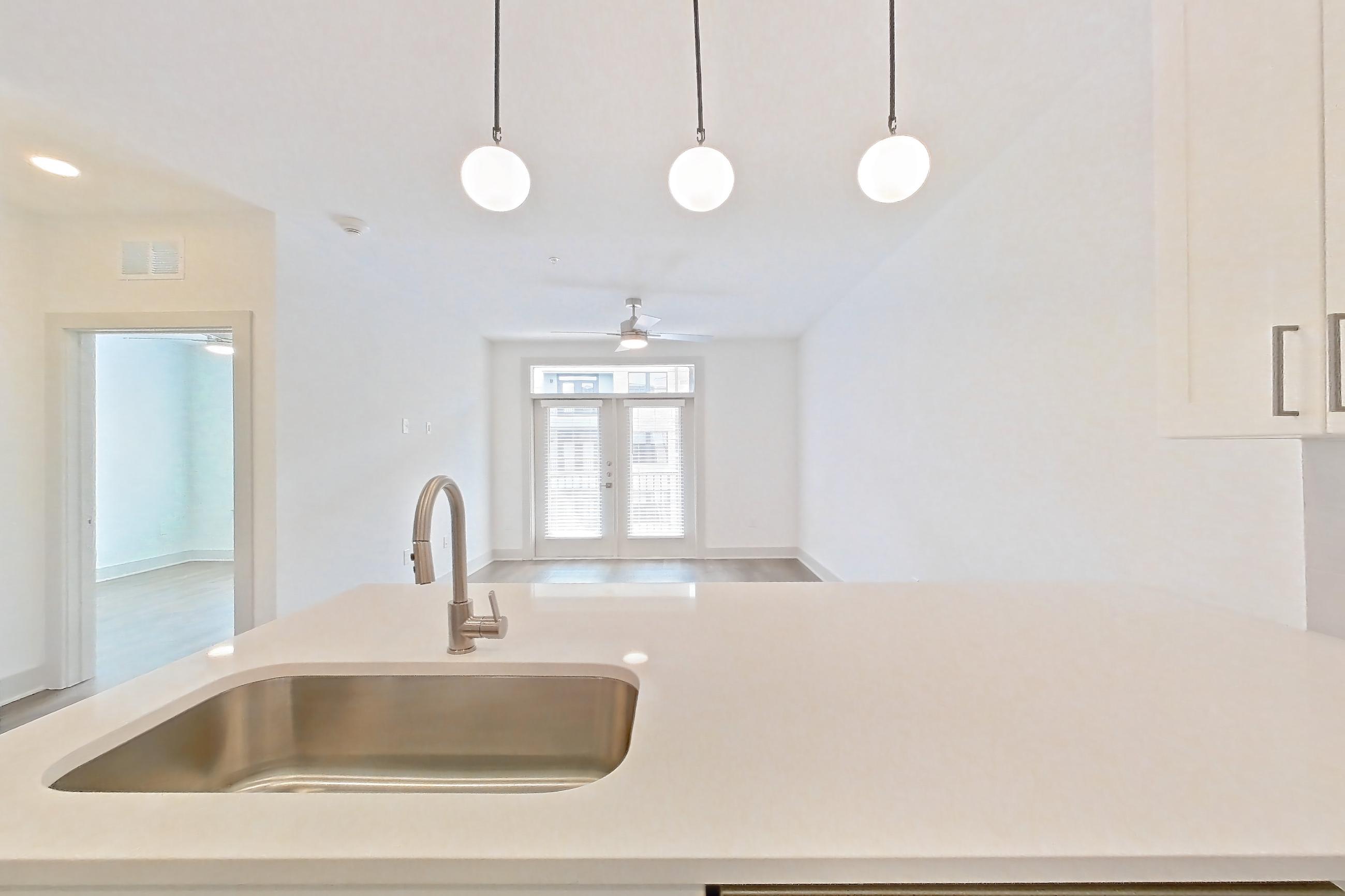 Kitchen with dishwasher, electric range, light countertops, light stone countertops, light wood-finish flooring, microwave, oven/range, and stainless steel appliances, Apartment 2344 at Groves South Congress