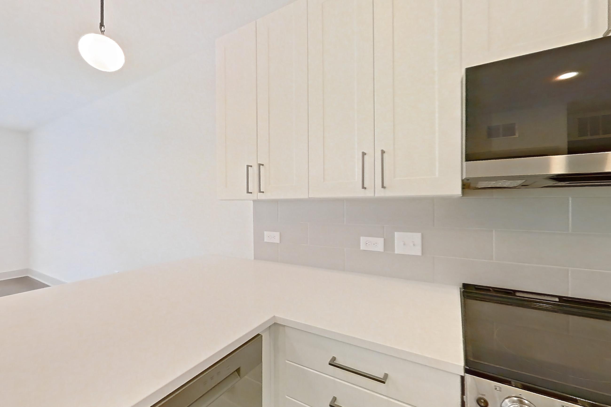 Kitchen with dishwasher, electric range, light countertops, light stone countertops, light wood-finish flooring, microwave, oven/range, and stainless steel appliances, Apartment 2344 at Groves South Congress