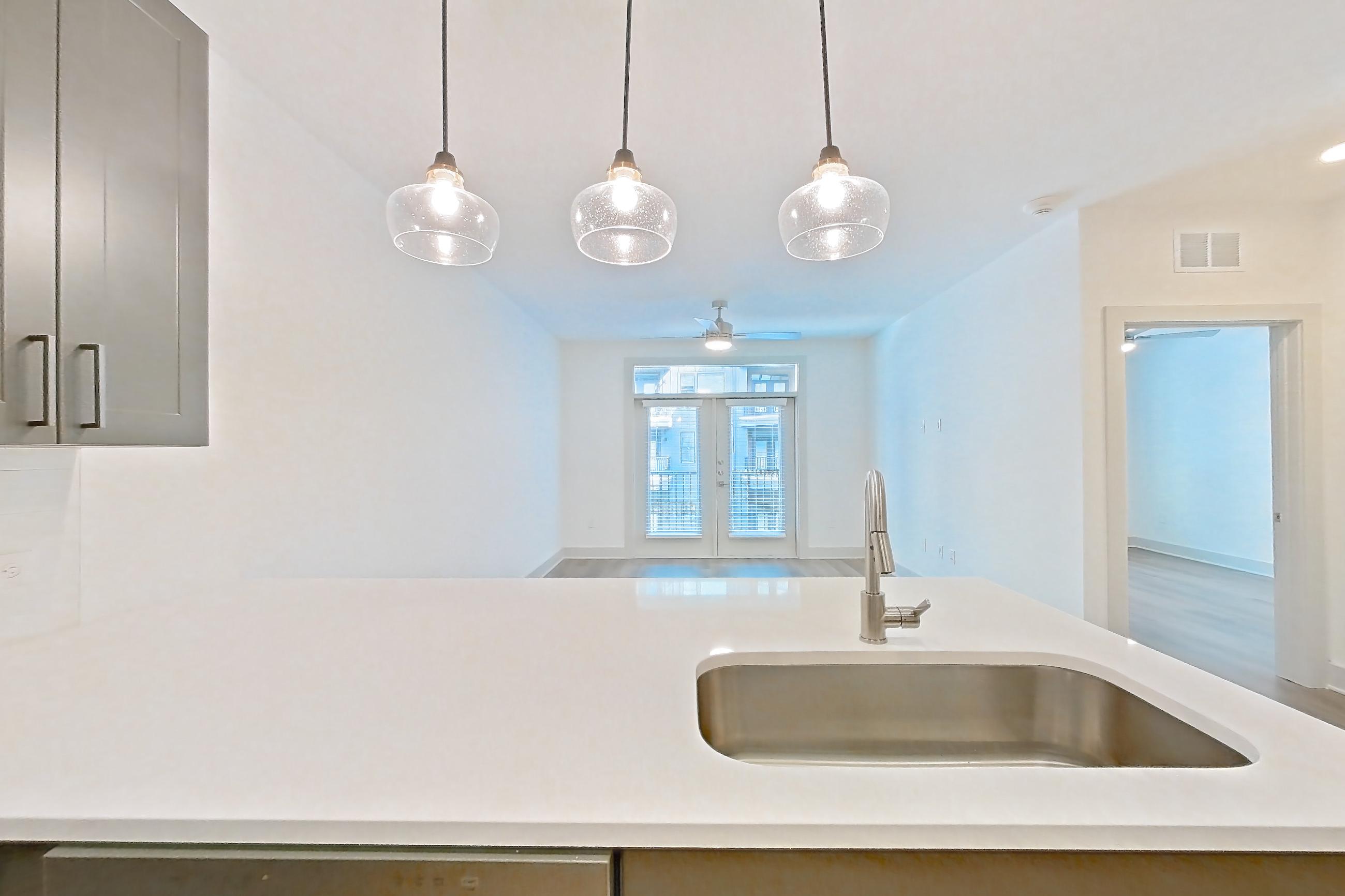 Kitchen with dishwasher, electric range, light countertops, light stone countertops, light wood-finish flooring, oven/range, and stainless steel appliances, Apartment 2203 at Groves South Congress