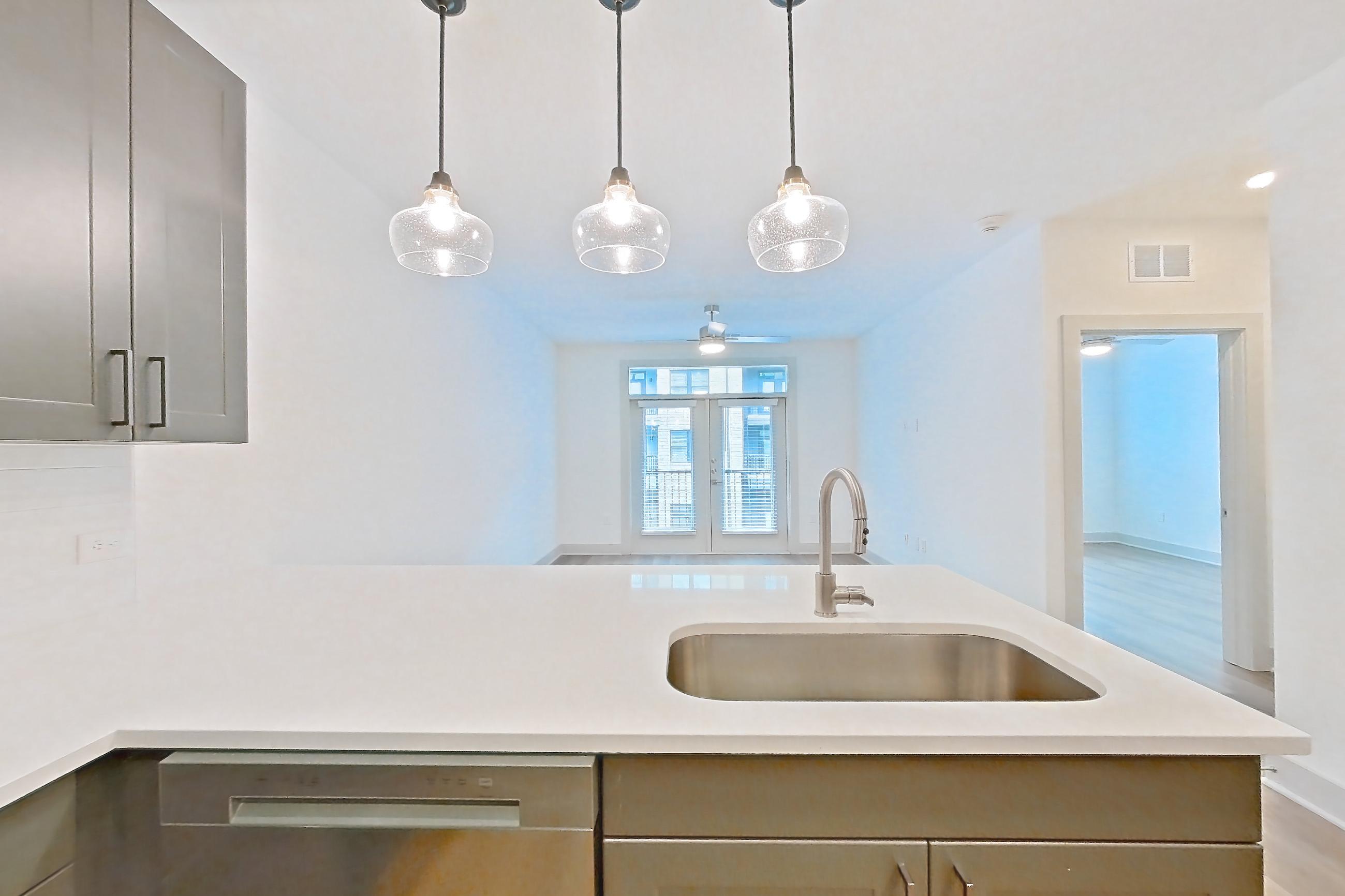 Kitchen with dishwasher, electric range, light countertops, light stone countertops, light wood-finish flooring, microwave, oven/range, and stainless steel appliances, Apartment 2205 at Groves South Congress