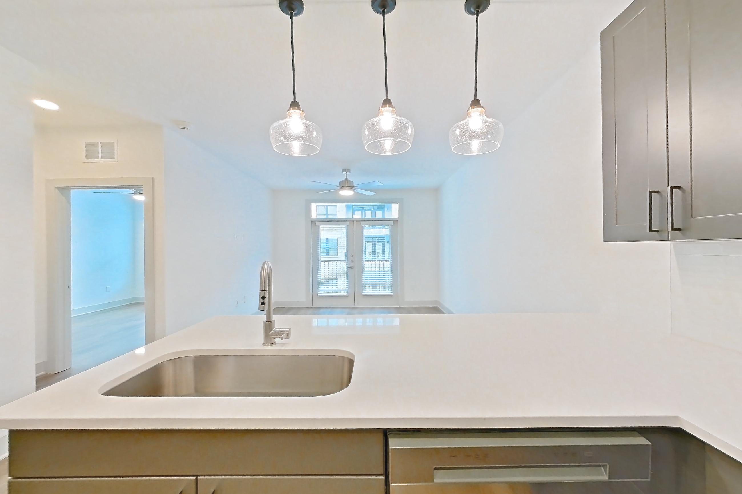 Kitchen with dishwasher, electric range, light countertops, light stone countertops, light wood-finish flooring, oven/range, and stainless steel appliances, Apartment 2207 at Groves South Congress