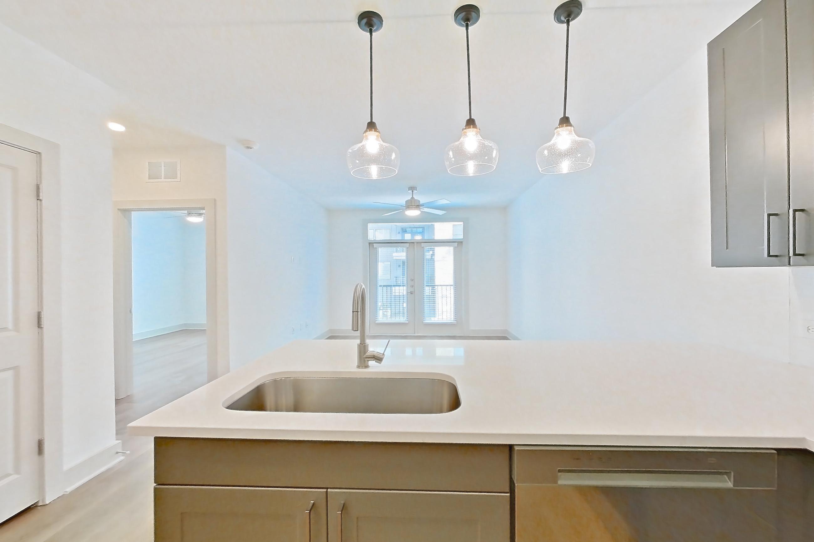 Kitchen with dishwasher, electric range, light countertops, light stone countertops, light wood-finish flooring, microwave, oven/range, and stainless steel appliances, Apartment 2209 at Groves South Congress