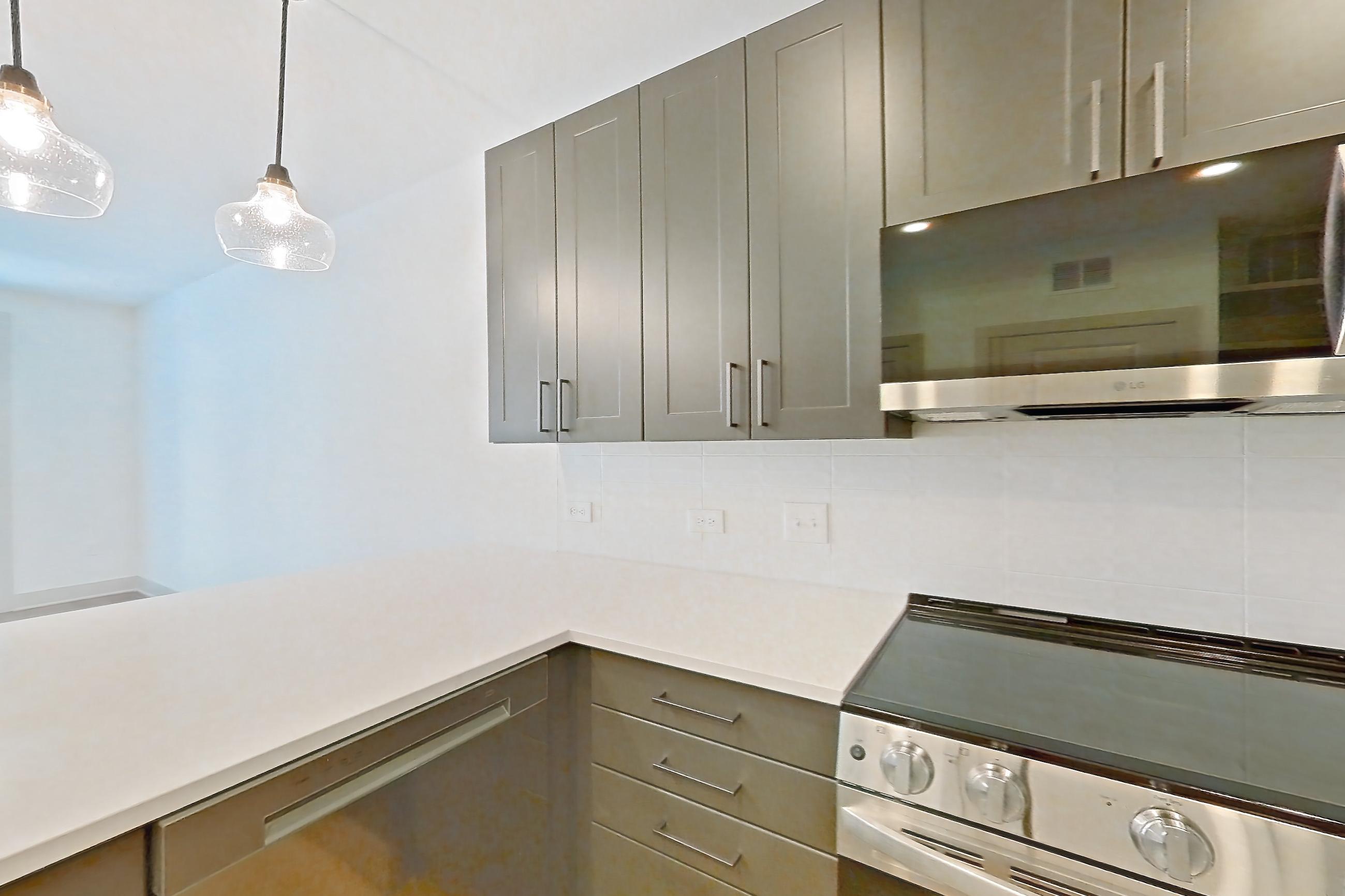 Kitchen with dishwasher, electric range, light countertops, light stone countertops, light wood-finish flooring, microwave, oven/range, and stainless steel appliances, Apartment 2209 at Groves South Congress