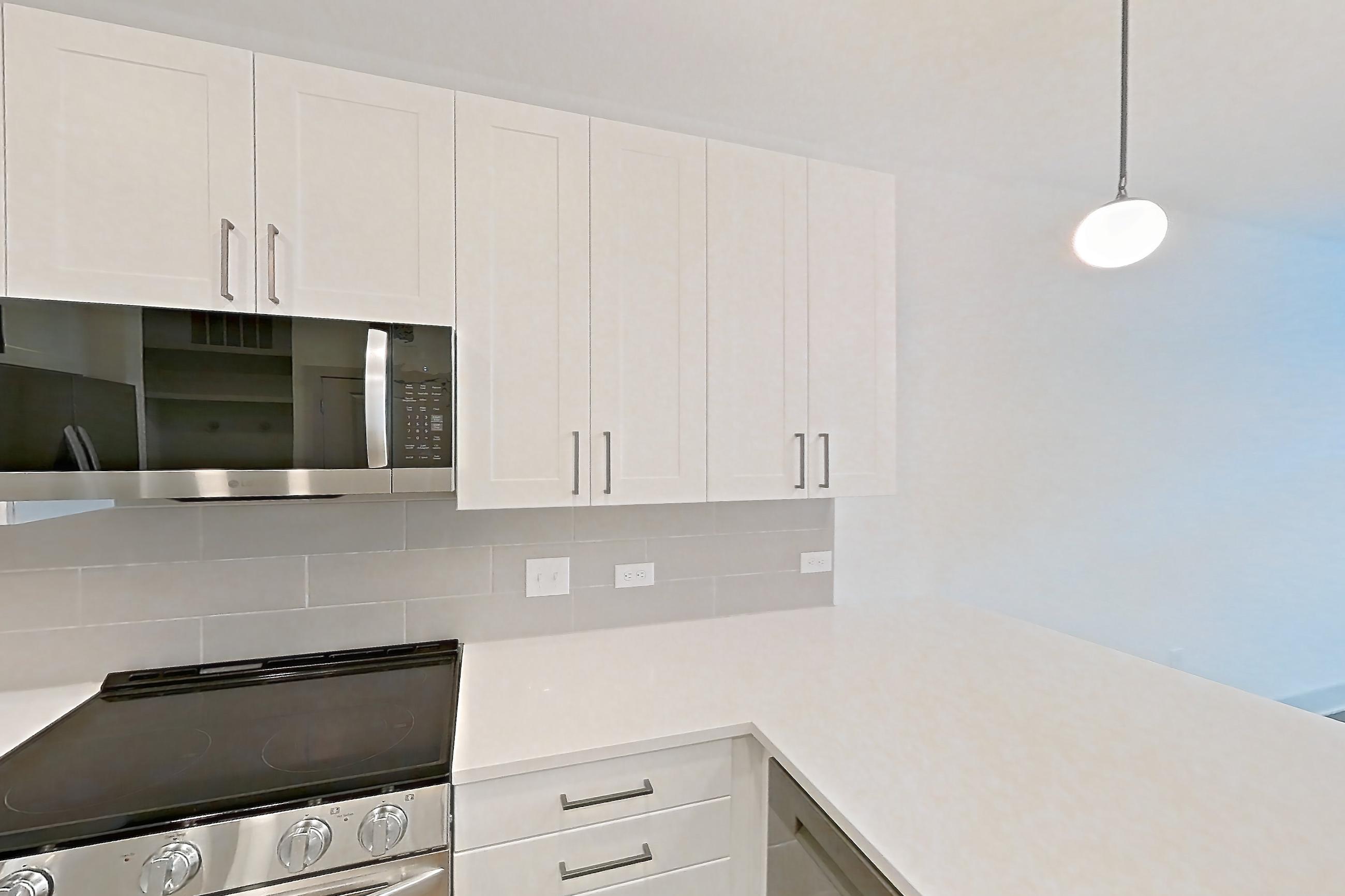 Kitchen with dark wood-finish flooring, dishwasher, electric range, light countertops, light stone countertops, oven/range, refrigerator, stainless steel appliances, and water & ice dispenser, Apartment 2303 at Groves South Congress
