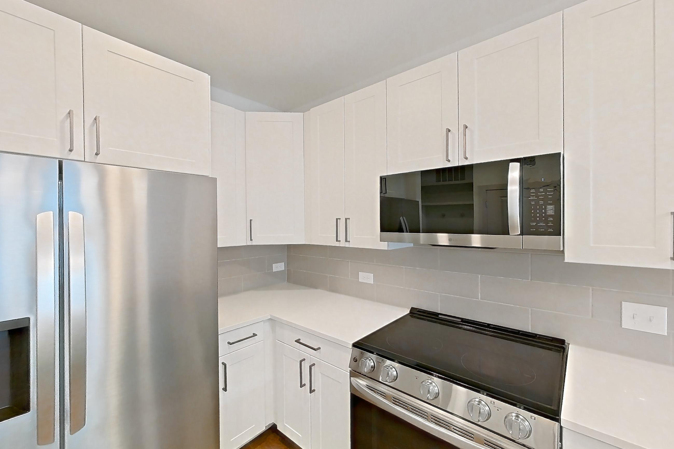 Kitchen with dark wood-finish flooring, dishwasher, electric range, light countertops, light stone countertops, oven/range, refrigerator, stainless steel appliances, and water & ice dispenser, Apartment 2303 at Groves South Congress