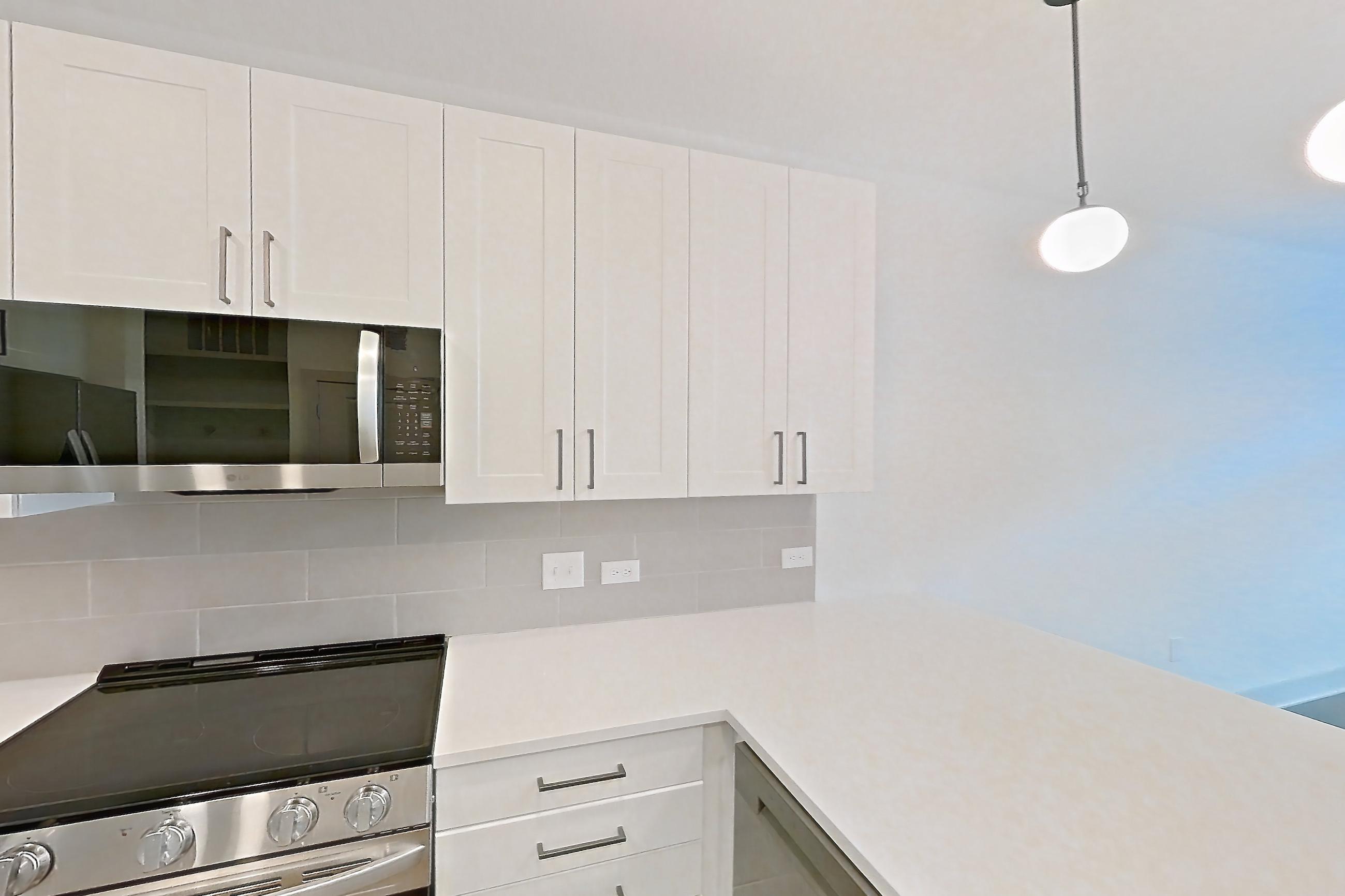 Kitchen with dark wood-finish flooring, dishwasher, electric range, light countertops, light stone countertops, light wood-finish flooring, oven/range, refrigerator, stainless steel appliances, and water & ice dispenser, Apartment 2305 at Groves South Congress