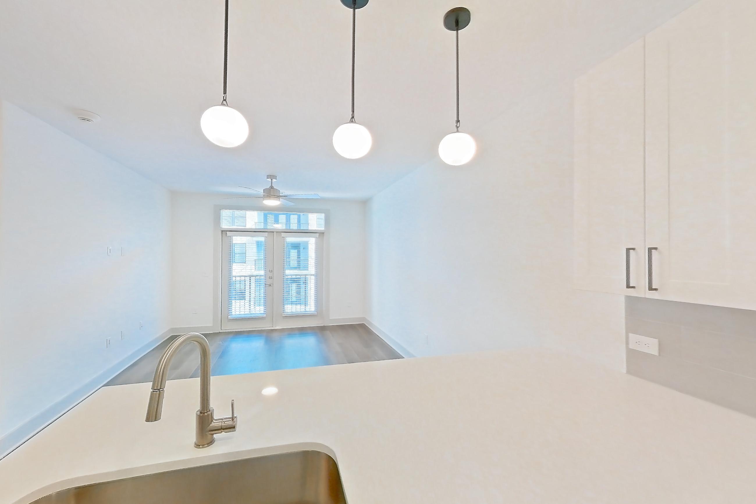 Kitchen with dark wood-finish flooring, dishwasher, electric range, light countertops, light stone countertops, light wood-finish flooring, oven/range, refrigerator, stainless steel appliances, and water & ice dispenser, Apartment 2307 at Groves South Congress