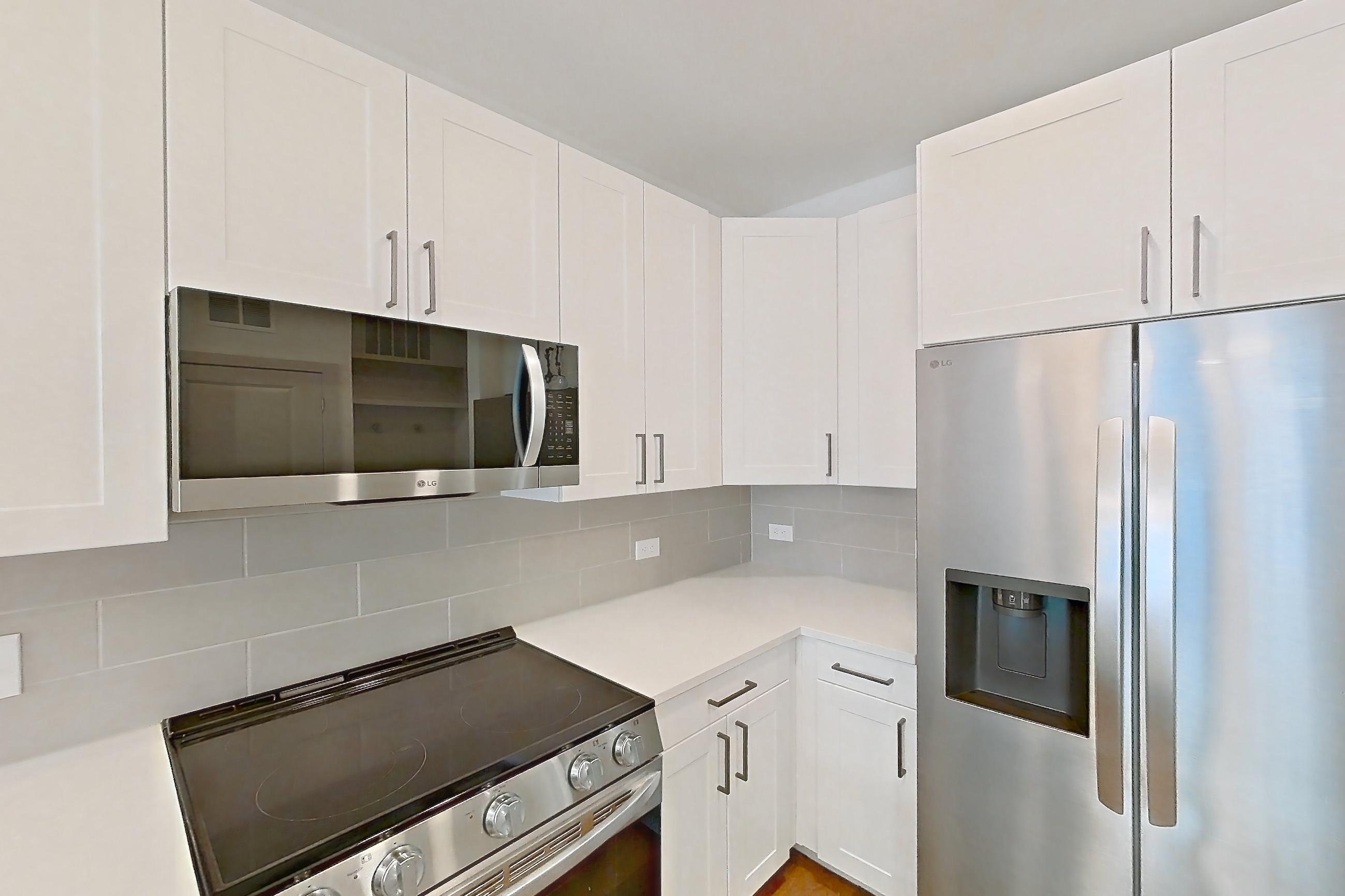Kitchen with dark wood-finish flooring, dishwasher, electric range, light countertops, light stone countertops, light wood-finish flooring, oven/range, refrigerator, stainless steel appliances, and water & ice dispenser, Apartment 2307 at Groves South Congress