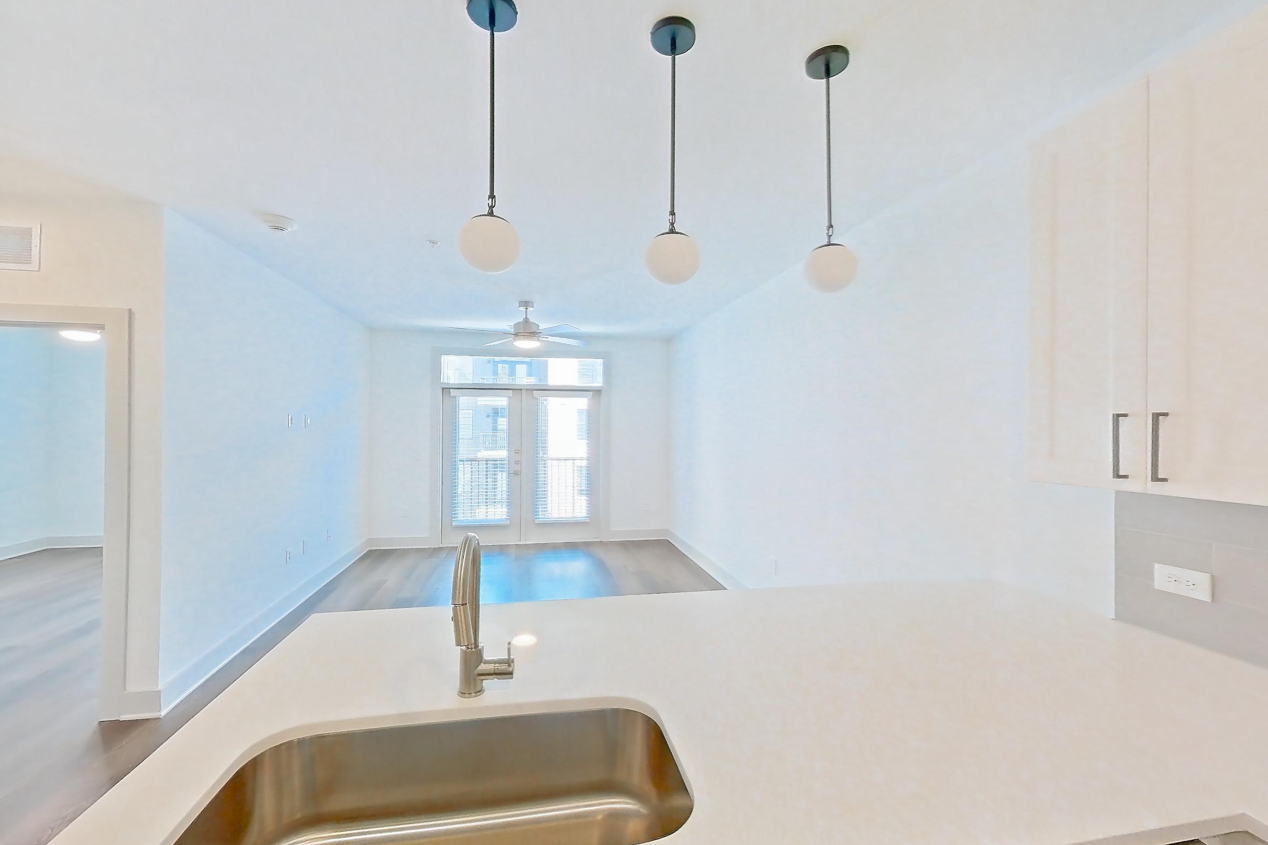 Kitchen with dishwasher, electric range, light countertops, light stone countertops, light wood-finish flooring, oven/range, refrigerator, stainless steel appliances, and water & ice dispenser, Apartment 2309 at Groves South Congress