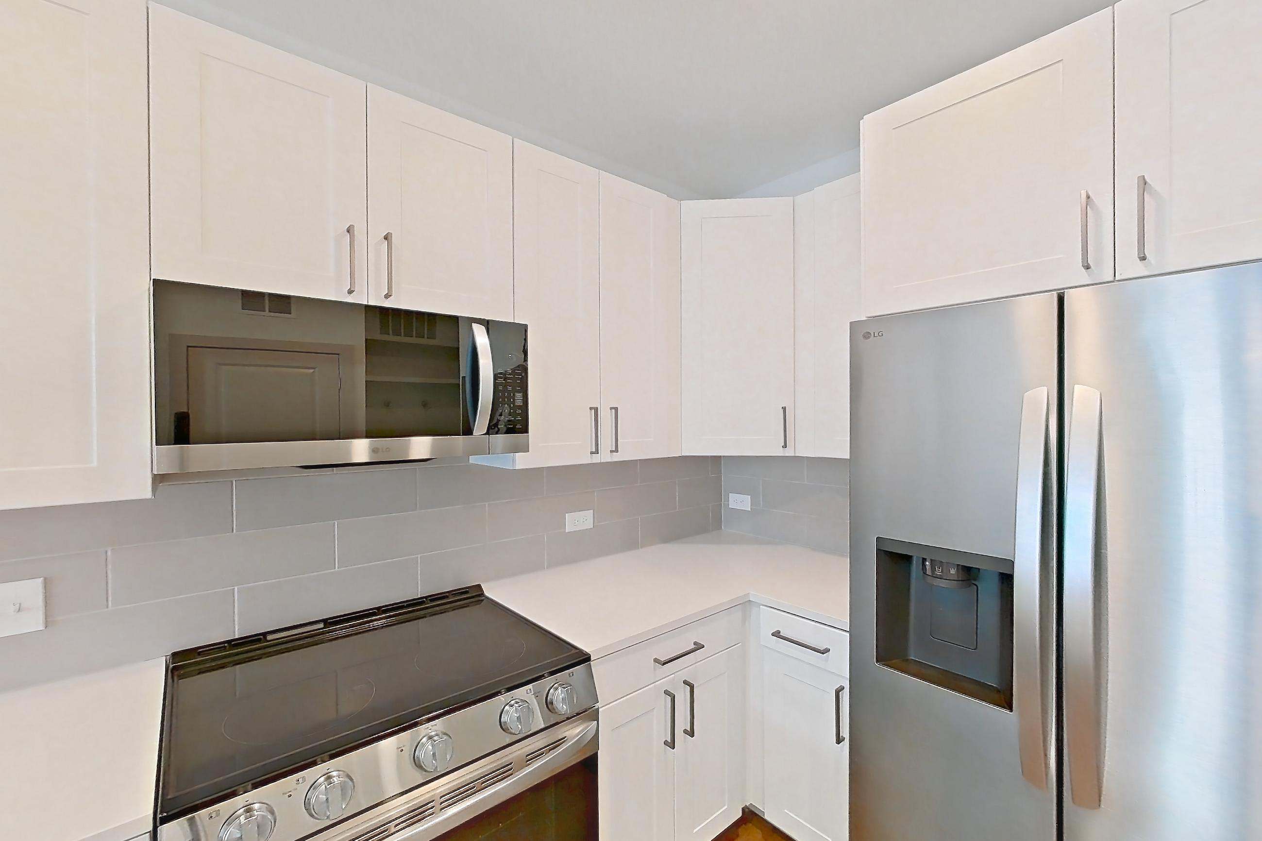 Kitchen with dishwasher, electric range, light countertops, light stone countertops, light wood-finish flooring, oven/range, refrigerator, stainless steel appliances, and water & ice dispenser, Apartment 2309 at Groves South Congress
