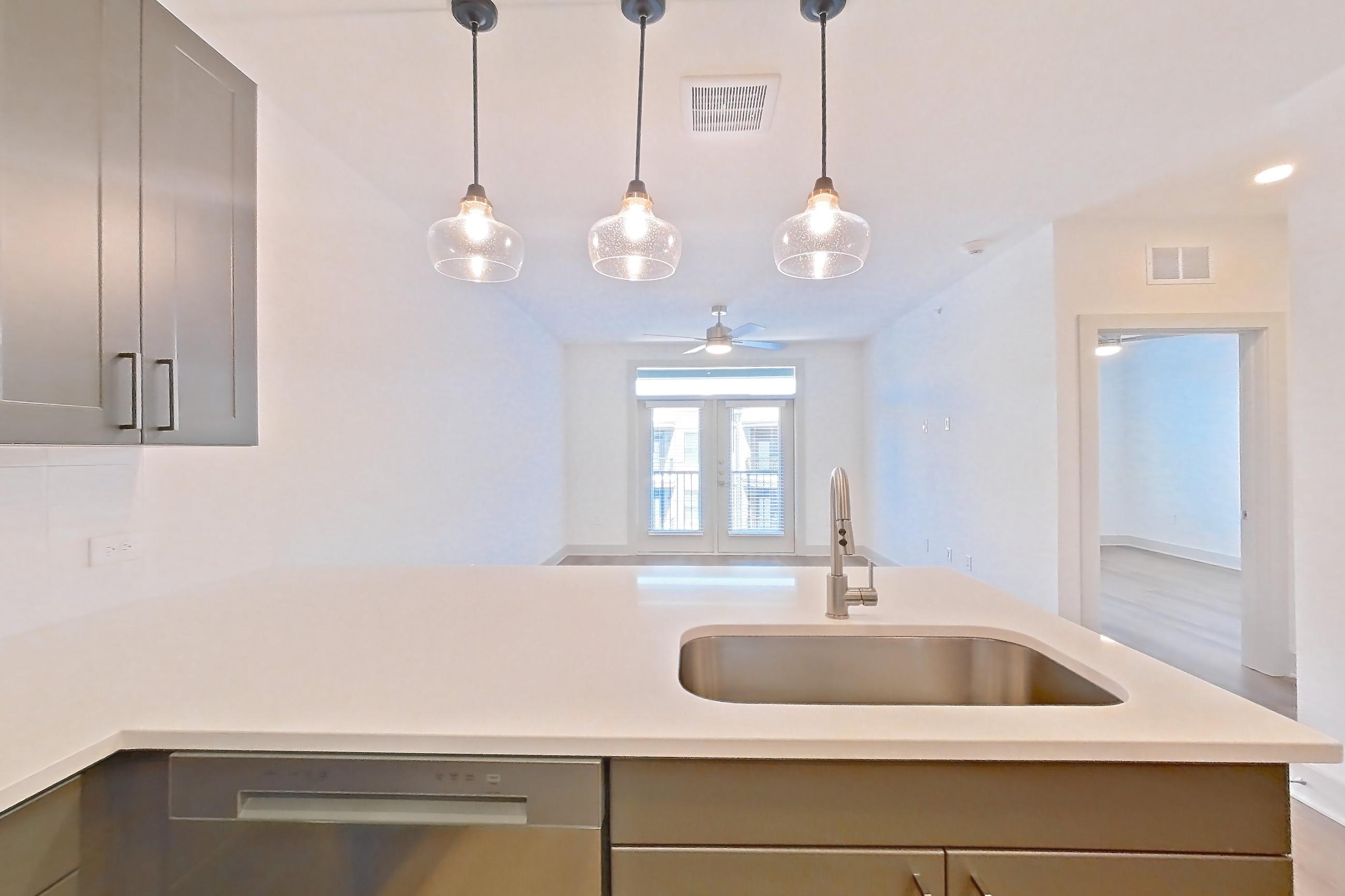 Kitchen with dishwasher, electric range, light countertops, light stone countertops, light wood-finish flooring, oven/range, and stainless steel appliances, Apartment 2403 at Groves South Congress