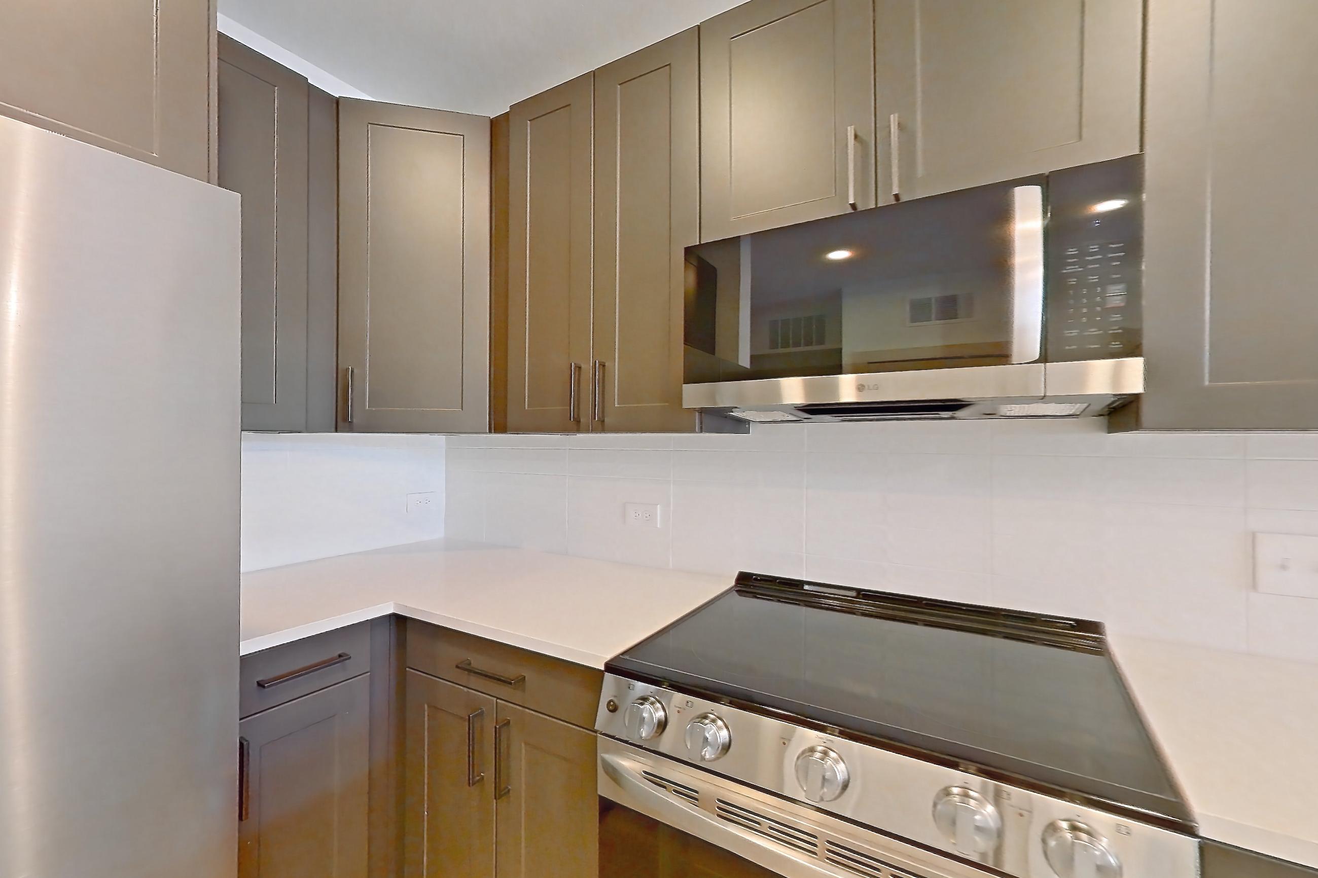Kitchen with dishwasher, electric range, light countertops, light stone countertops, light wood-finish flooring, oven/range, and stainless steel appliances, Apartment 2403 at Groves South Congress