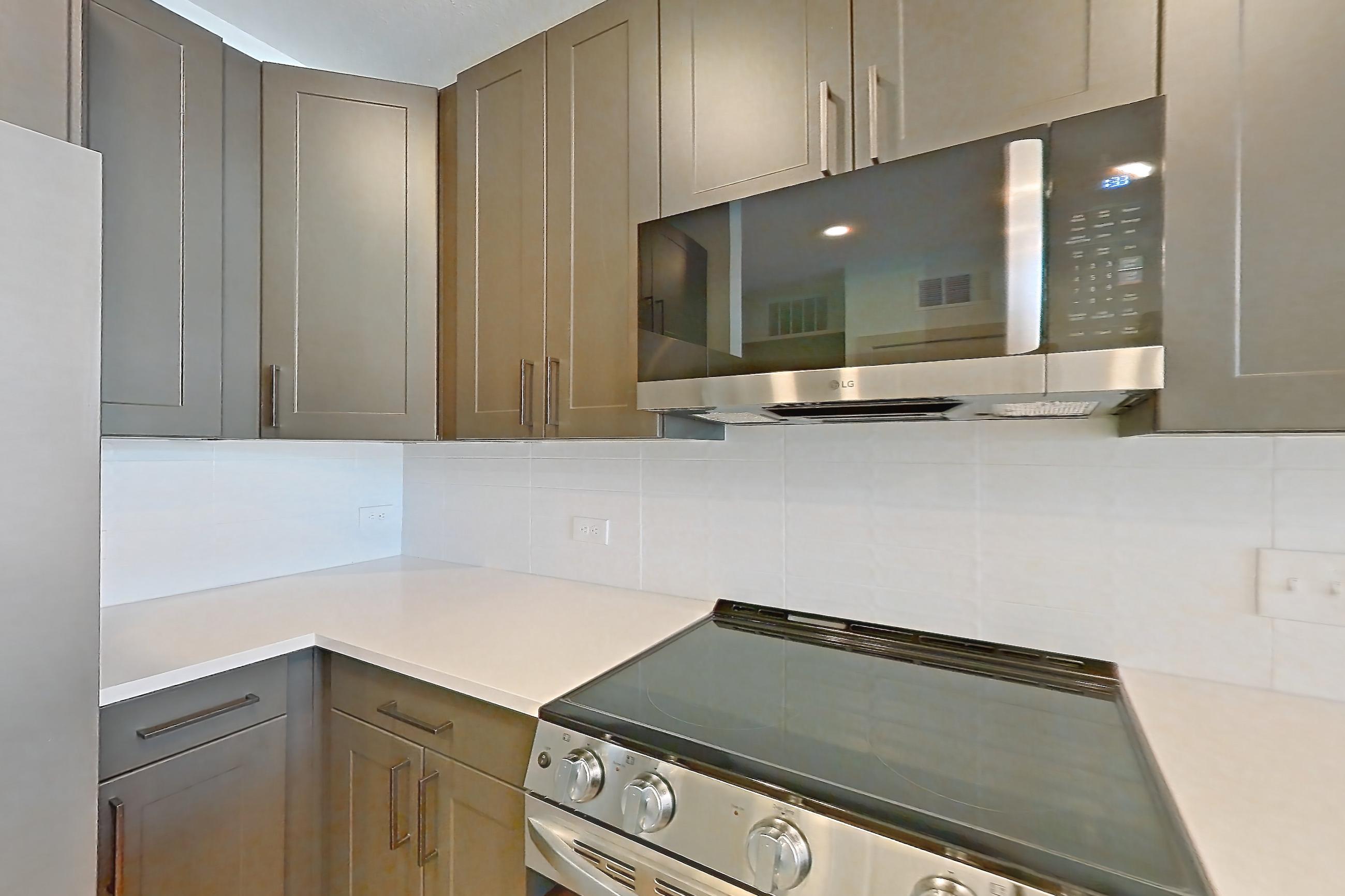 Kitchen with dishwasher, electric range, light countertops, light stone countertops, light wood-finish flooring, microwave, oven/range, and stainless steel appliances, Apartment 2405 at Groves South Congress