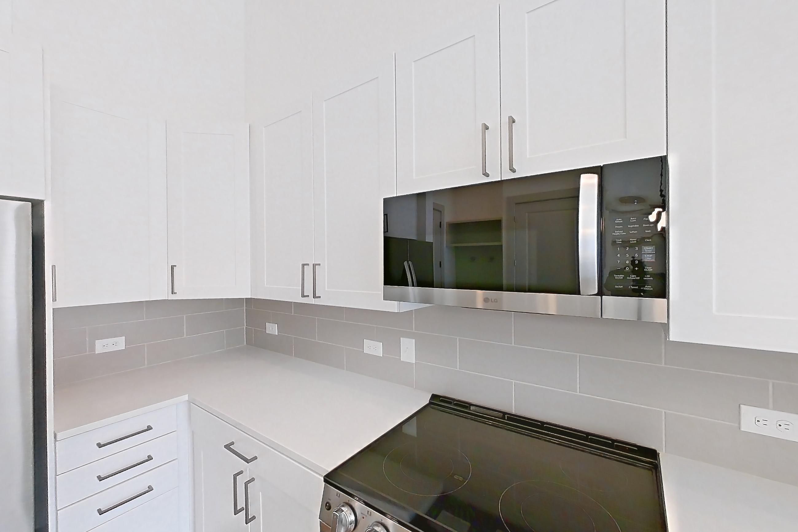 Kitchen with electric range, light countertops, light wood-finish flooring, oven/range, refrigerator, stainless steel appliances, and water & ice dispenser, Apartment 2149 at Groves South Congress