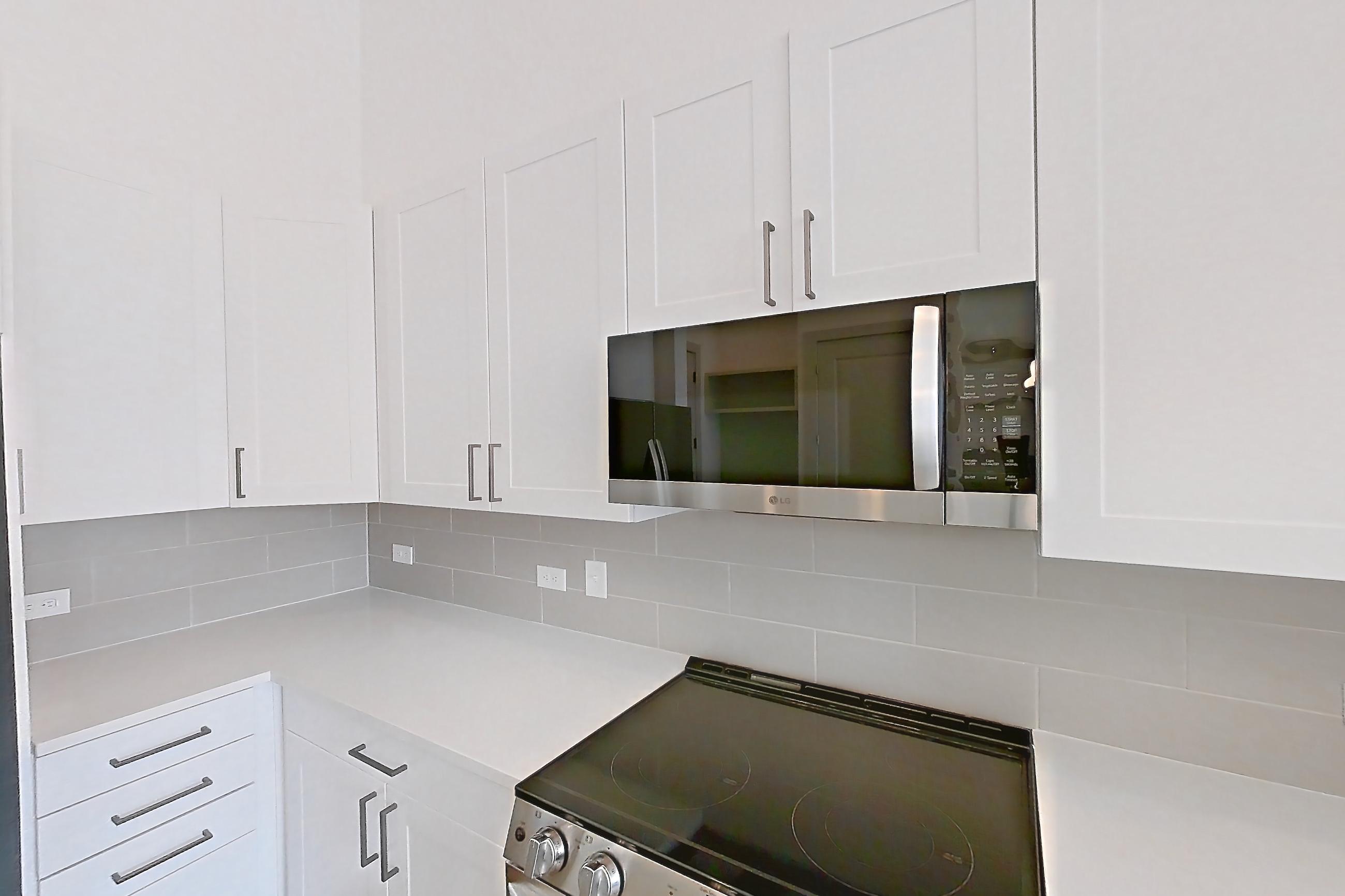 Kitchen with electric range, light countertops, light wood-finish flooring, oven/range, refrigerator, stainless steel appliances, and water & ice dispenser, Apartment 2153 at Groves South Congress