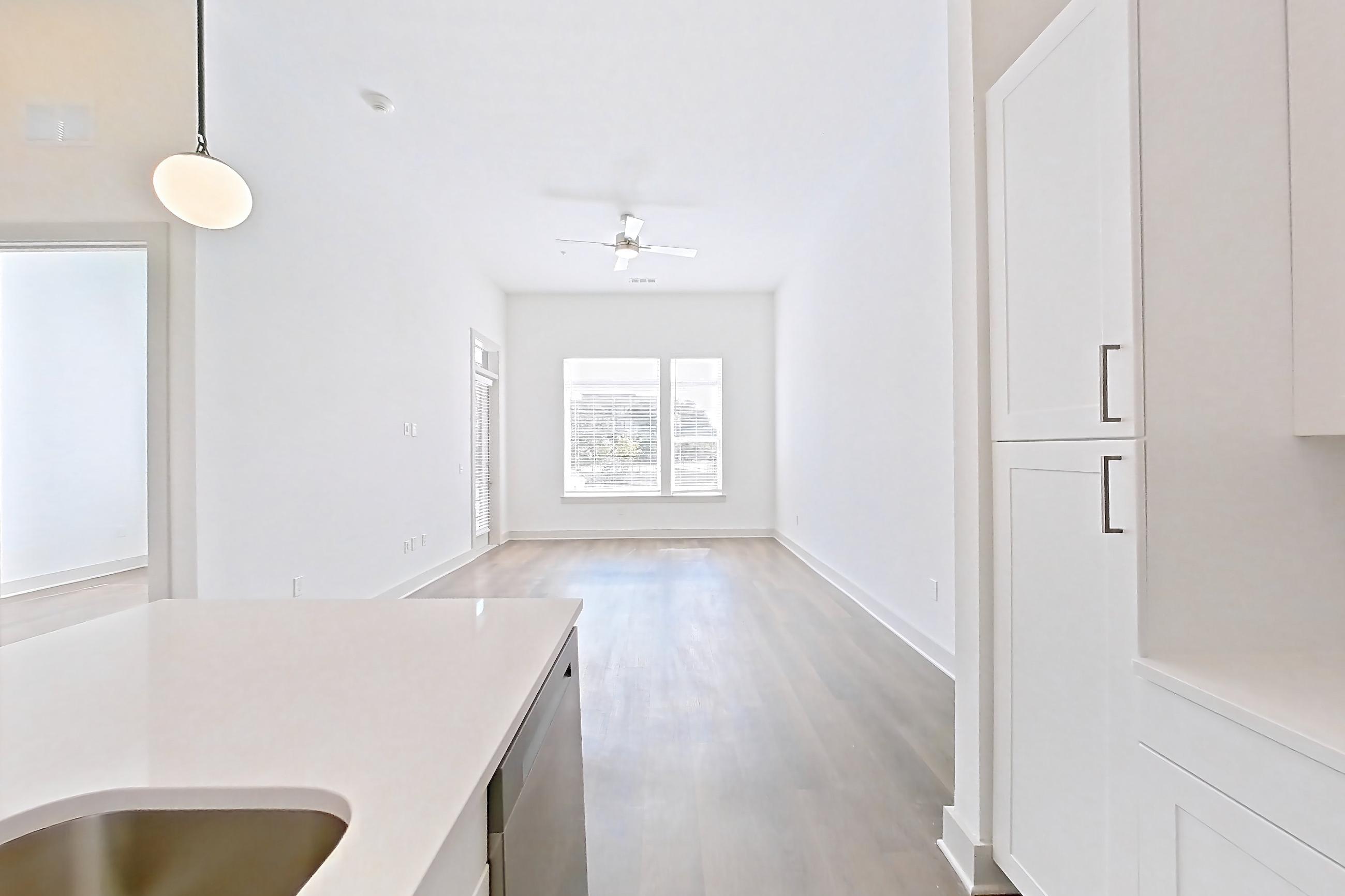 Kitchen with dark wood-finish flooring, dishwasher, electric range, light countertops, light stone countertops, microwave, oven/range, and stainless steel appliances, Apartment 2155 at Groves South Congress