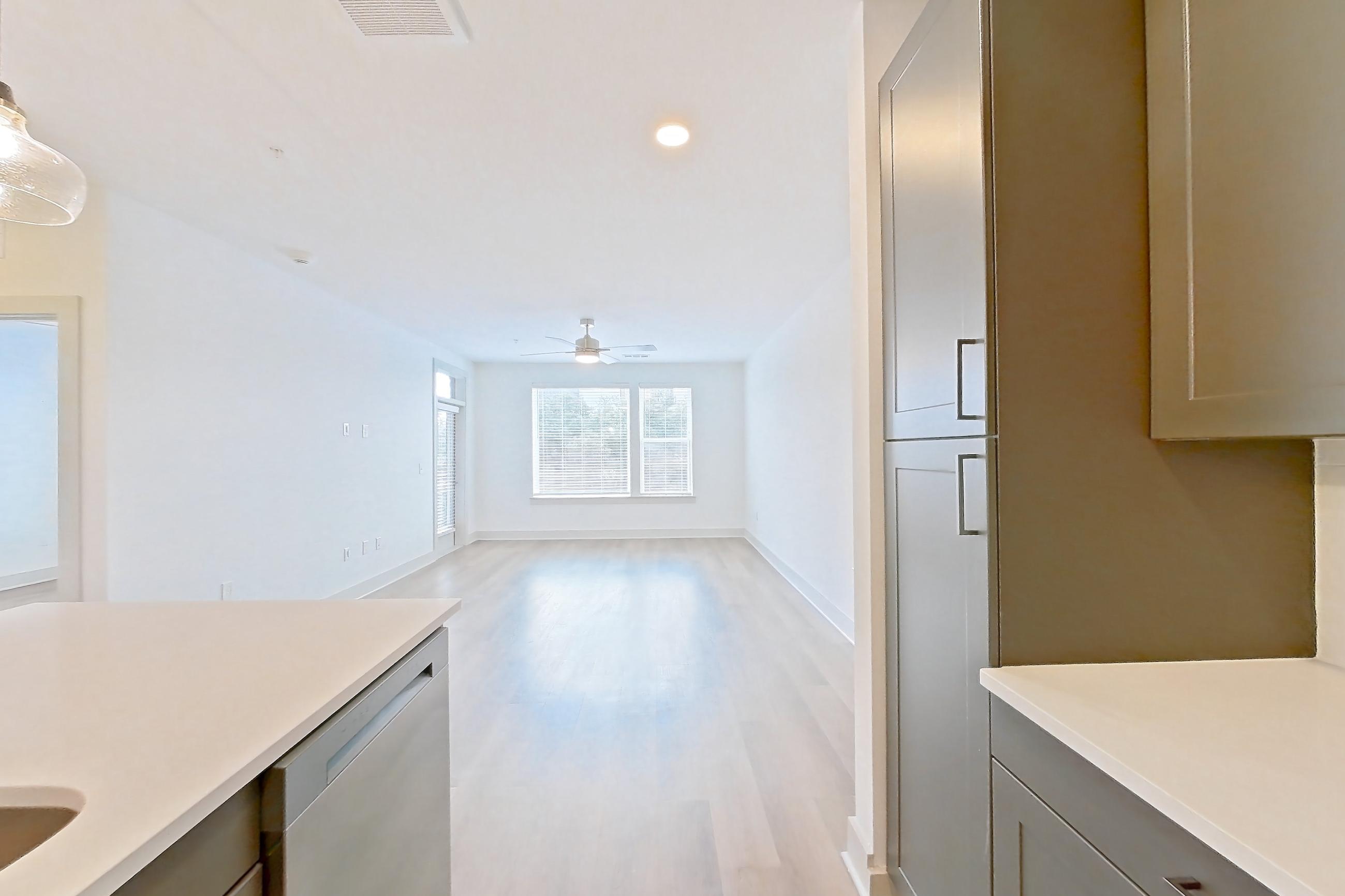 Kitchen with dishwasher, electric range, kitchen island, light countertops, light wood-finish flooring, oven/range, and stainless steel appliances, Apartment 2248 at Groves South Congress