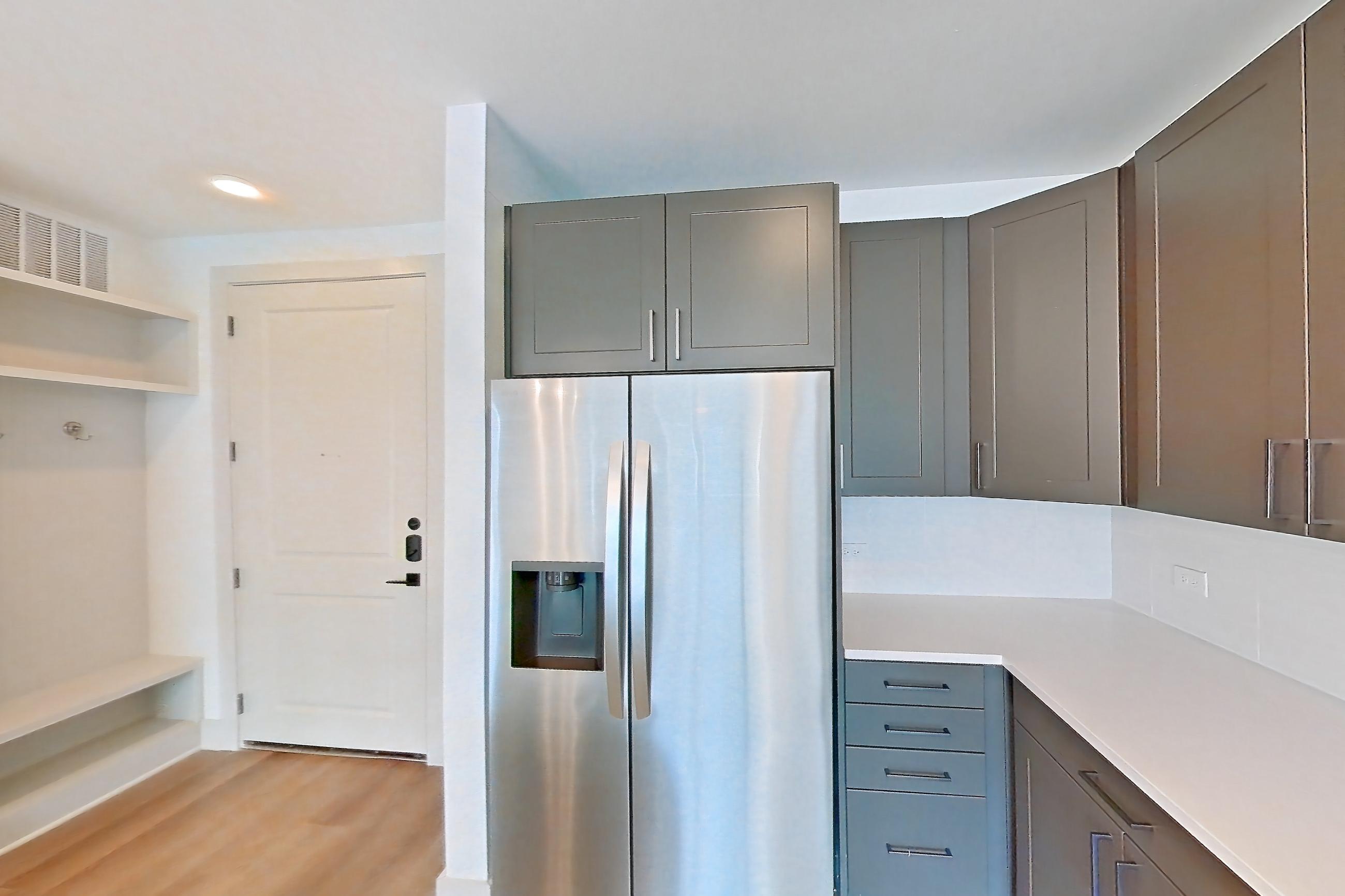 Kitchen with electric range, light countertops, light wood-finish flooring, oven/range, refrigerator, stainless steel appliances, and water & ice dispenser, Apartment 2249 at Groves South Congress