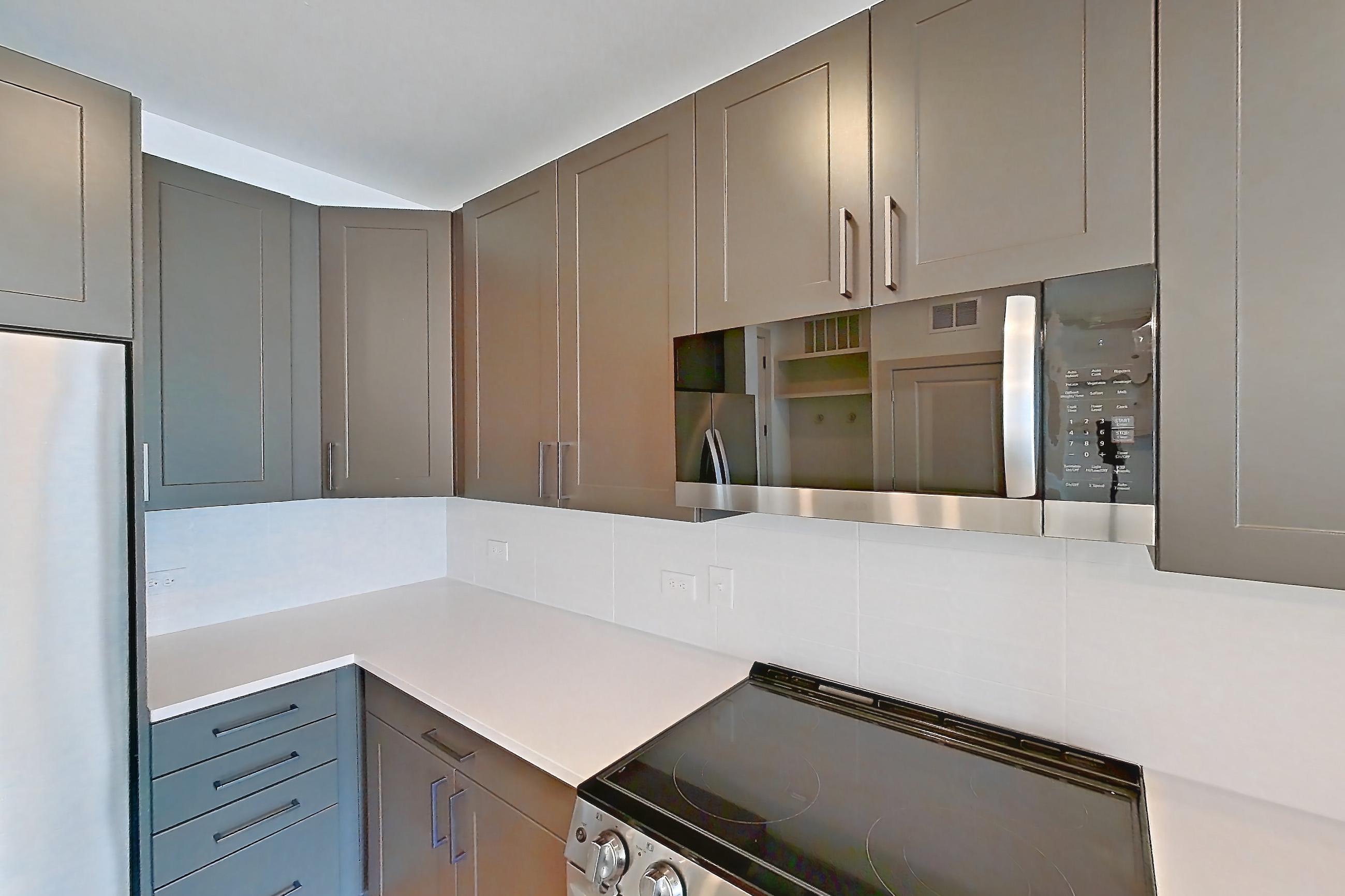 Kitchen with electric range, light countertops, light wood-finish flooring, oven/range, refrigerator, stainless steel appliances, and water & ice dispenser, Apartment 2249 at Groves South Congress