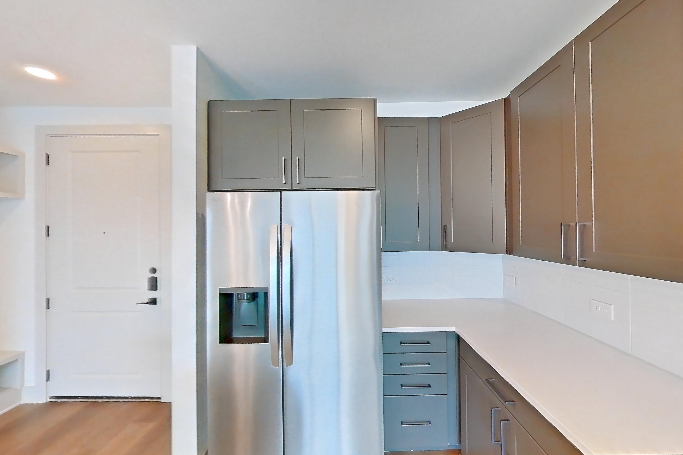 Kitchen with cooktop, electric cooktop, electric range, light countertops, light wood-finish flooring, oven/range, refrigerator, stainless steel appliances, and water & ice dispenser, Apartment 2253 at Groves South Congress