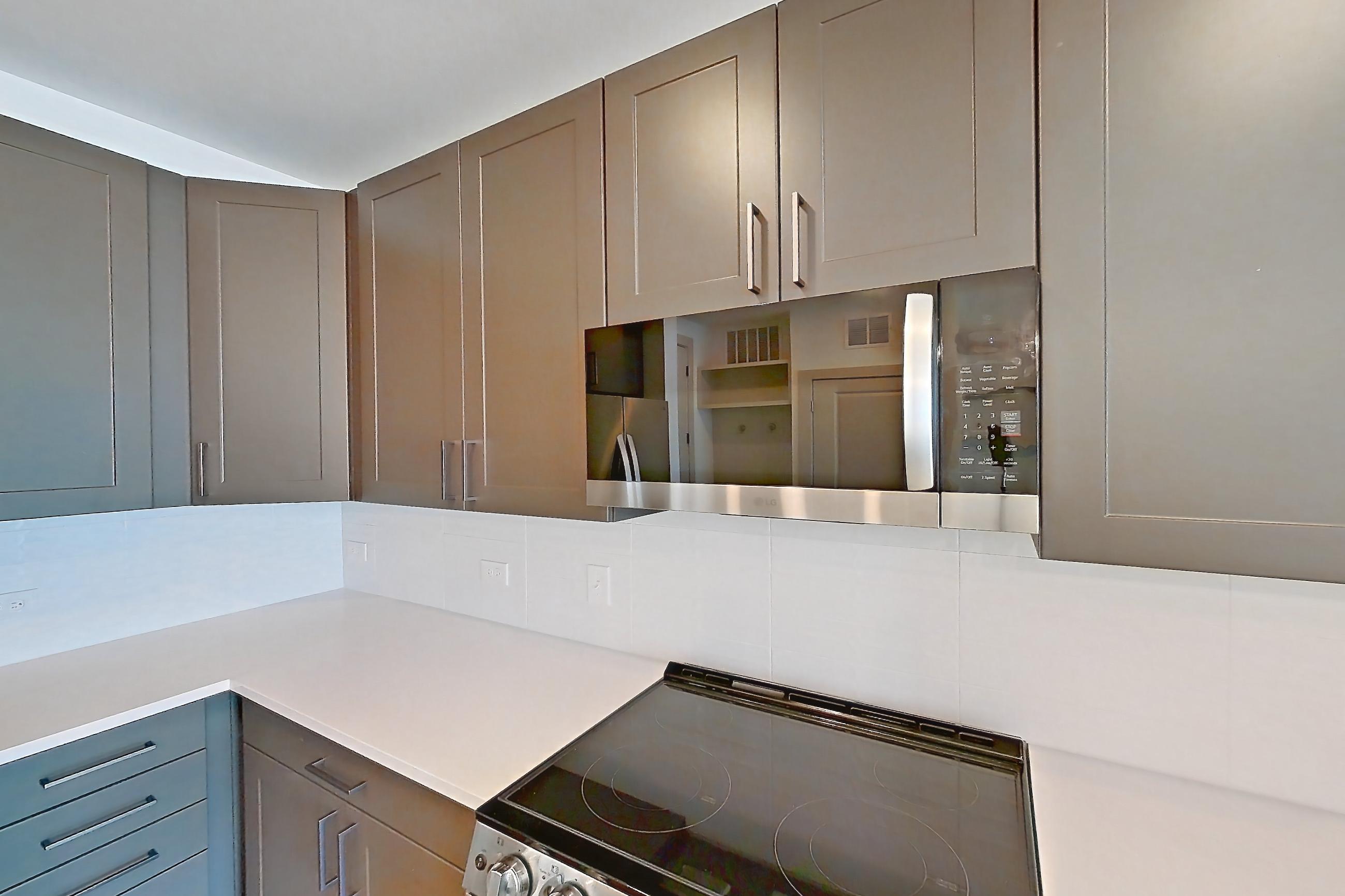 Kitchen with cooktop, electric cooktop, electric range, light countertops, light wood-finish flooring, oven/range, refrigerator, stainless steel appliances, and water & ice dispenser, Apartment 2253 at Groves South Congress