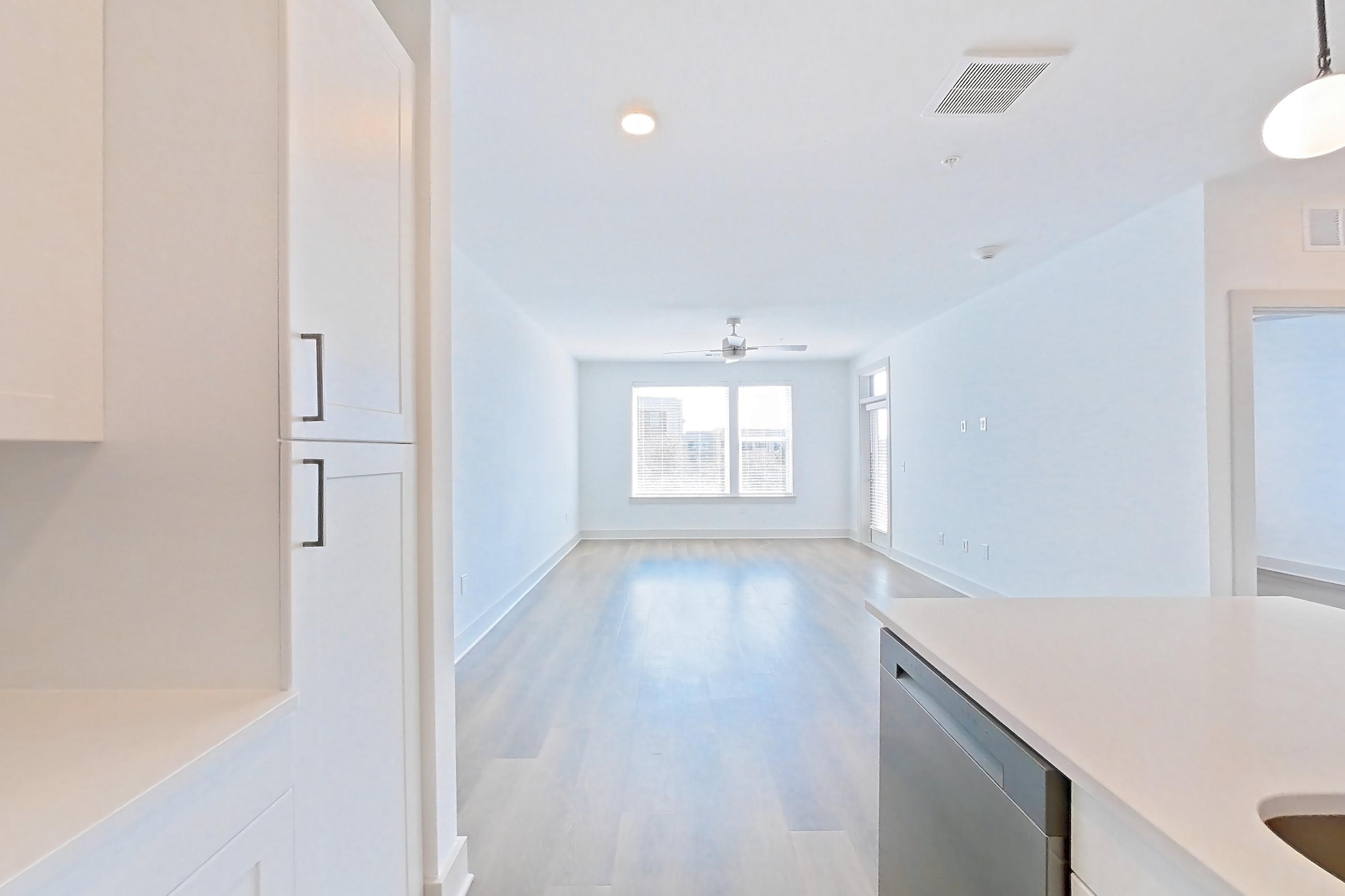 Kitchen with dark wood-finish flooring, dishwasher, electric range, kitchen island, light countertops, light stone countertops, microwave, oven/range, and stainless steel appliances, Apartment 2349 at Groves South Congress