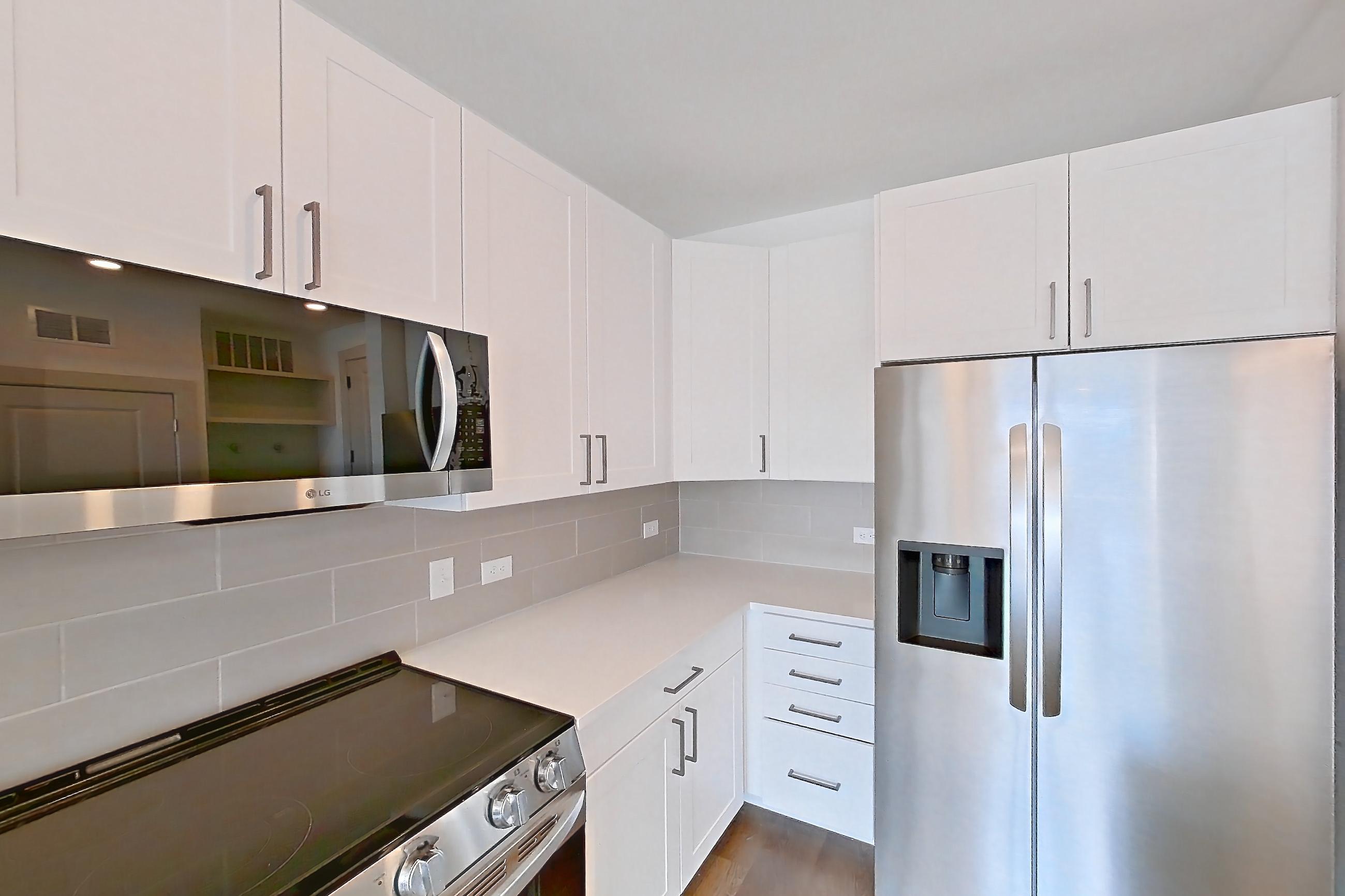 Kitchen with dark wood-finish flooring, electric range, light countertops, oven/range, refrigerator, stainless steel appliances, water & ice dispenser, and white appliances, Apartment 2351 at Groves South Congress