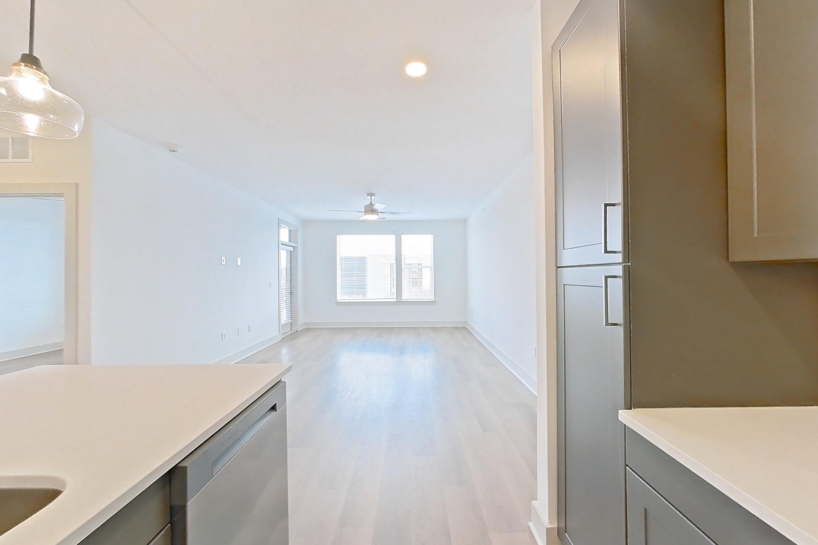 Kitchen with dishwasher, electric range, kitchen island, light countertops, light wood-finish flooring, oven/range, and stainless steel appliances, Apartment 2448 at Groves South Congress