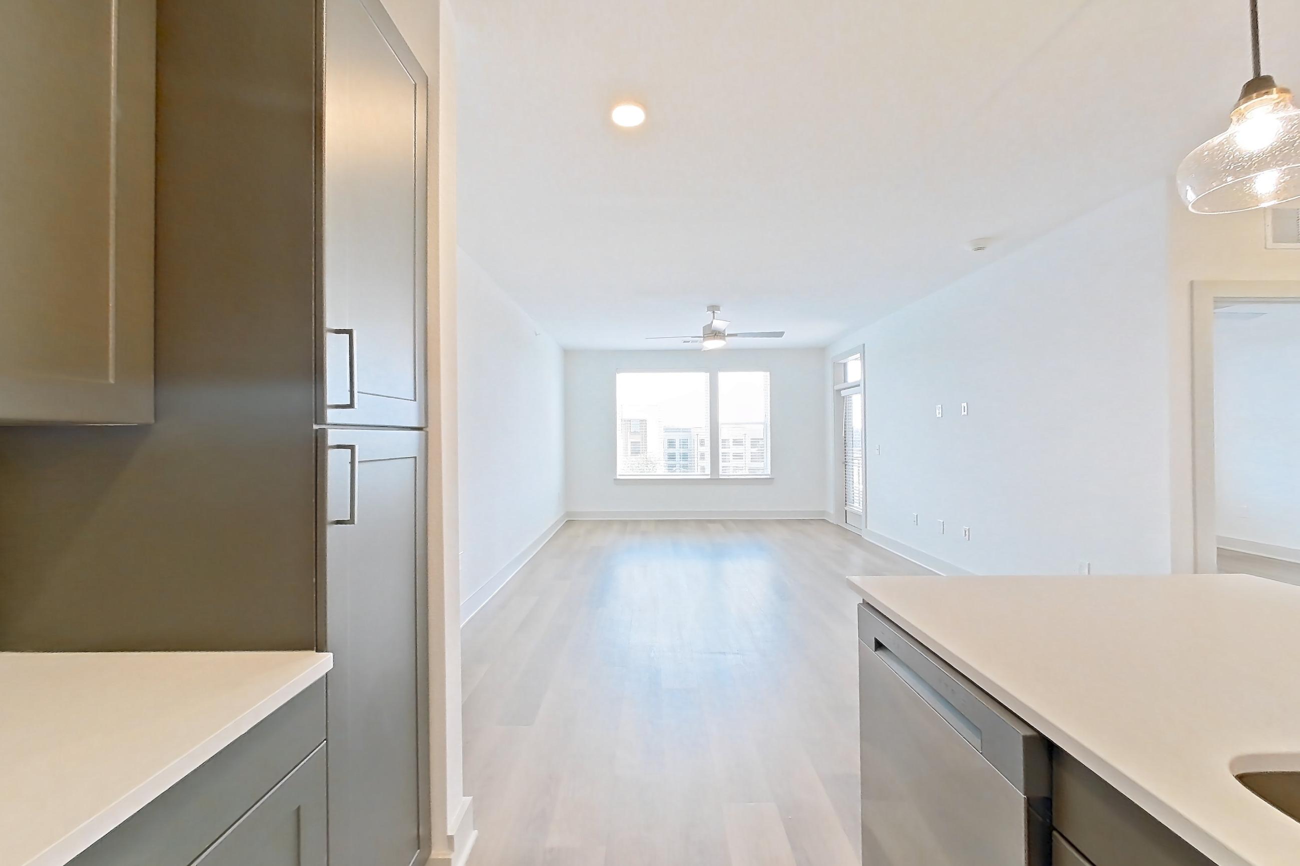Kitchen with dishwasher, electric range, kitchen island, light countertops, light wood-finish flooring, oven/range, and stainless steel appliances, Apartment 2449 at Groves South Congress