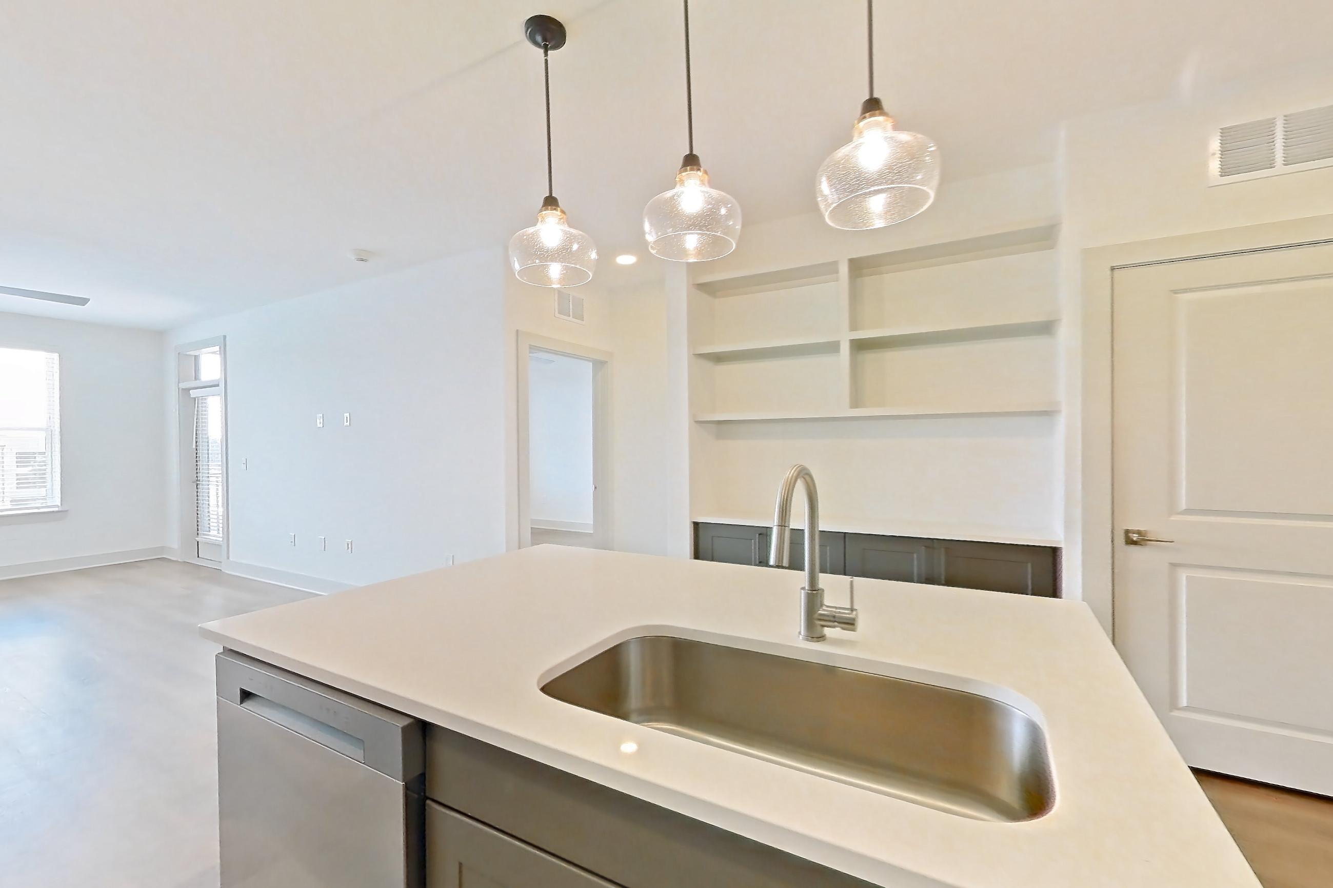 Kitchen with dishwasher, electric range, kitchen island, light countertops, light wood-finish flooring, oven/range, and stainless steel appliances, Apartment 2449 at Groves South Congress
