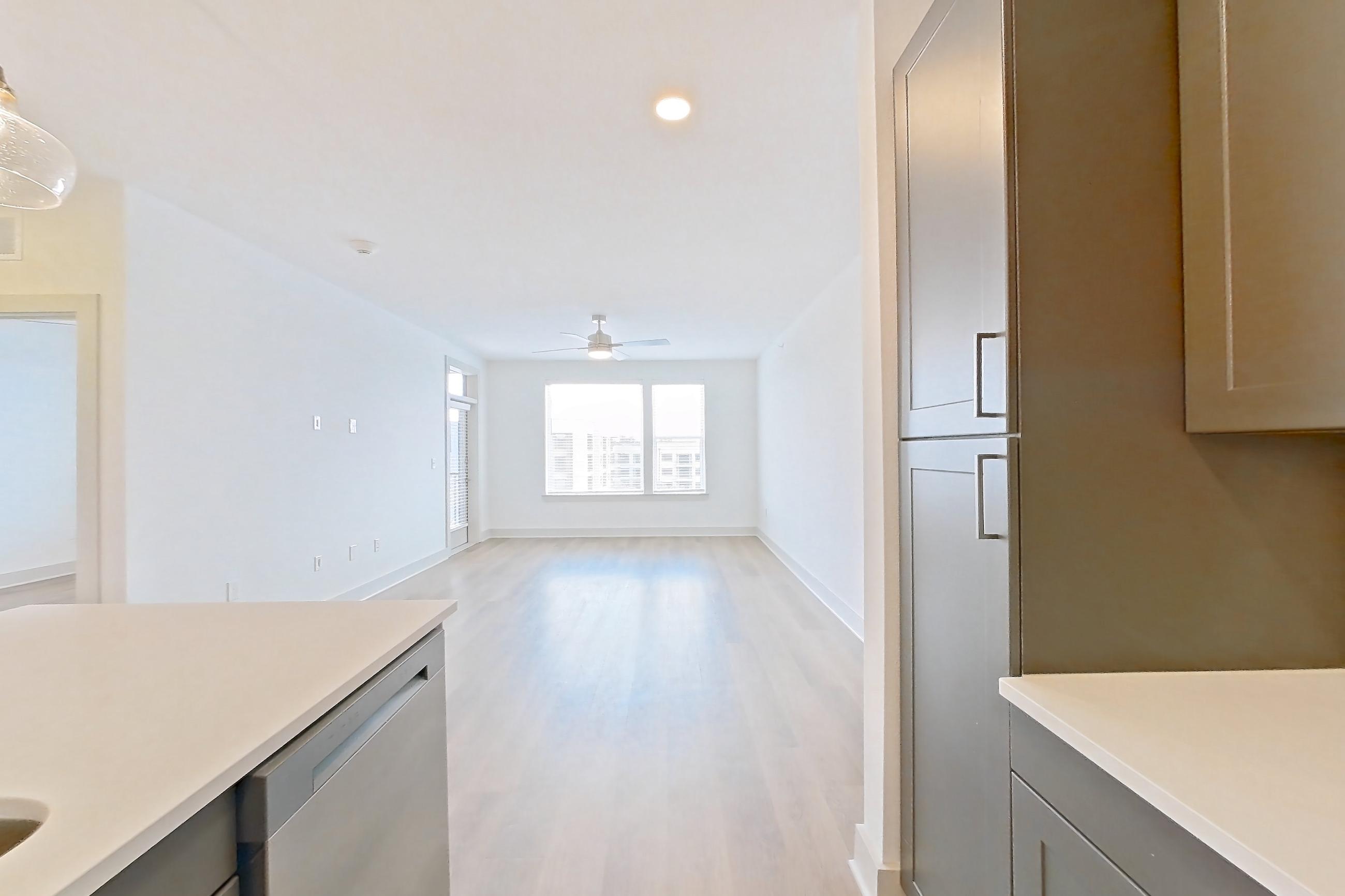 Kitchen with dishwasher, electric range, kitchen island, light countertops, light wood-finish flooring, oven/range, and stainless steel appliances, Apartment 2451 at Groves South Congress