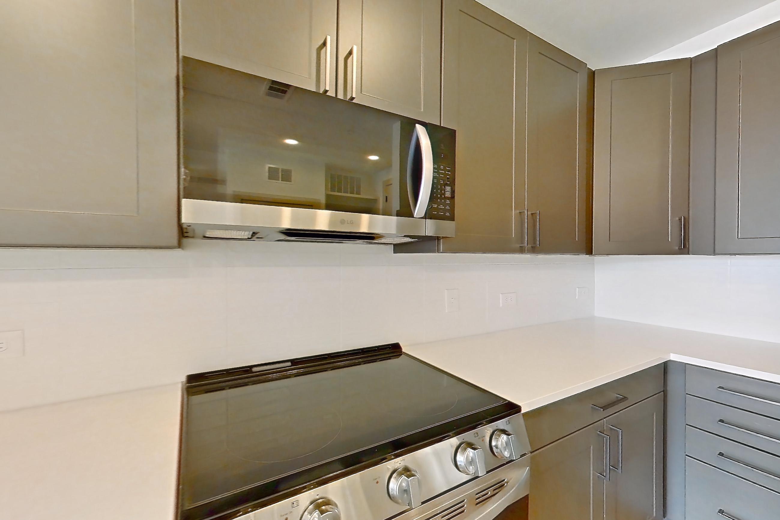 Kitchen with dishwasher, electric range, kitchen island, light countertops, light wood-finish flooring, oven/range, and stainless steel appliances, Apartment 2451 at Groves South Congress