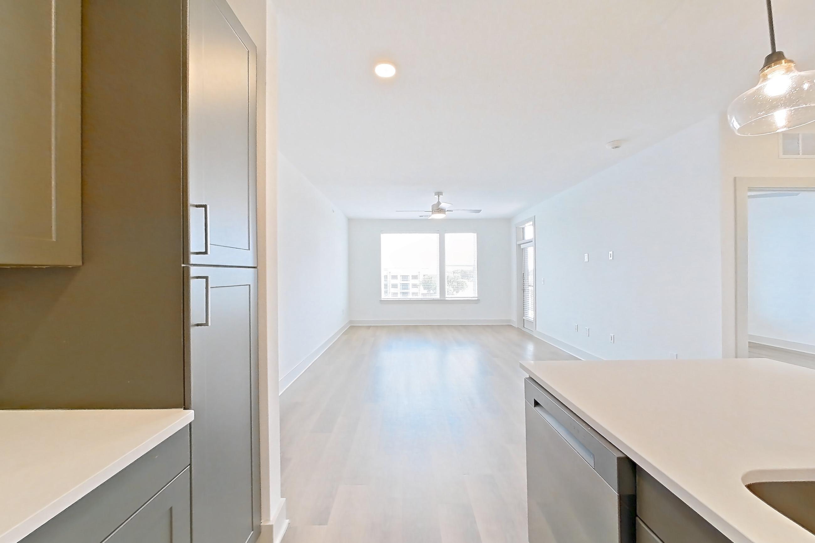 Kitchen with dishwasher, electric range, kitchen island, light countertops, light wood-finish flooring, oven/range, and stainless steel appliances, Apartment 2453 at Groves South Congress