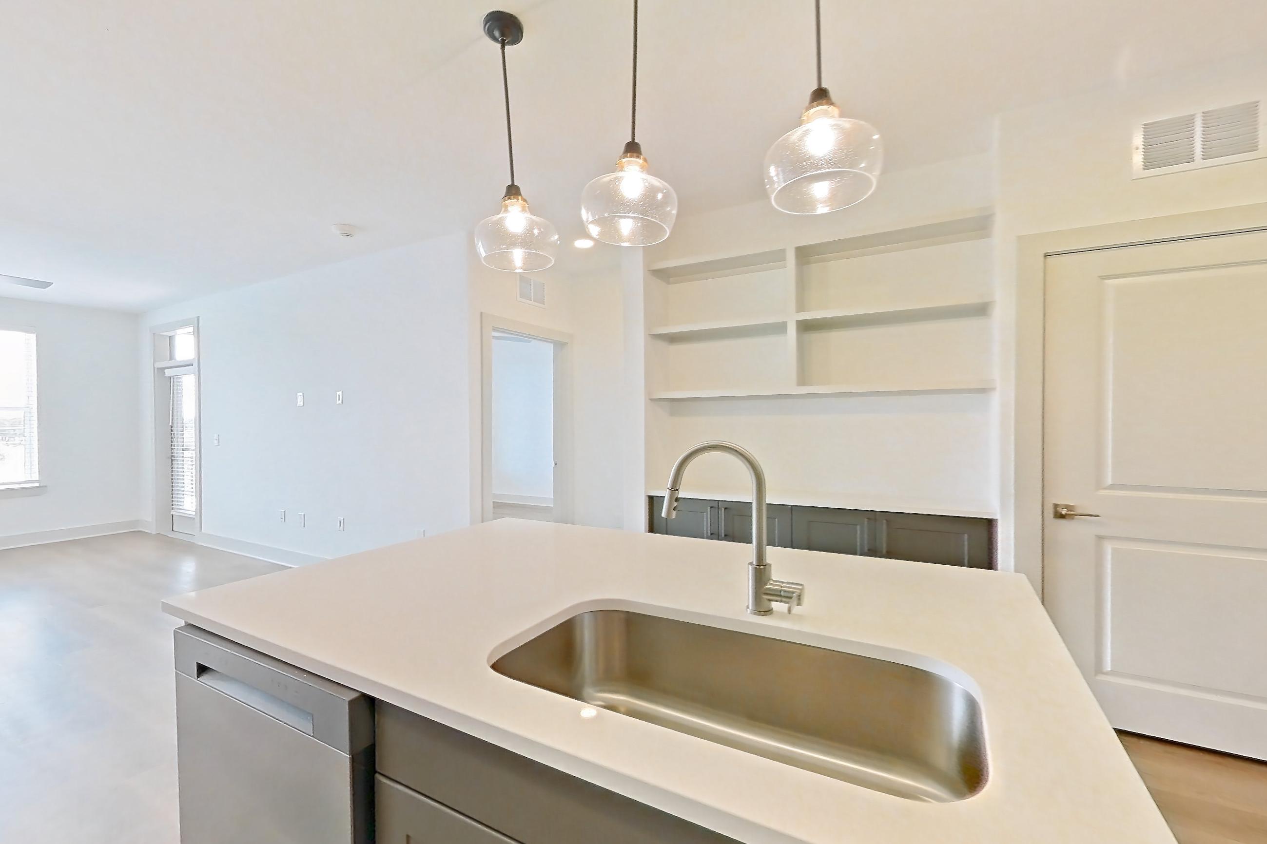 Kitchen with dishwasher, electric range, kitchen island, light countertops, light wood-finish flooring, oven/range, and stainless steel appliances, Apartment 2453 at Groves South Congress
