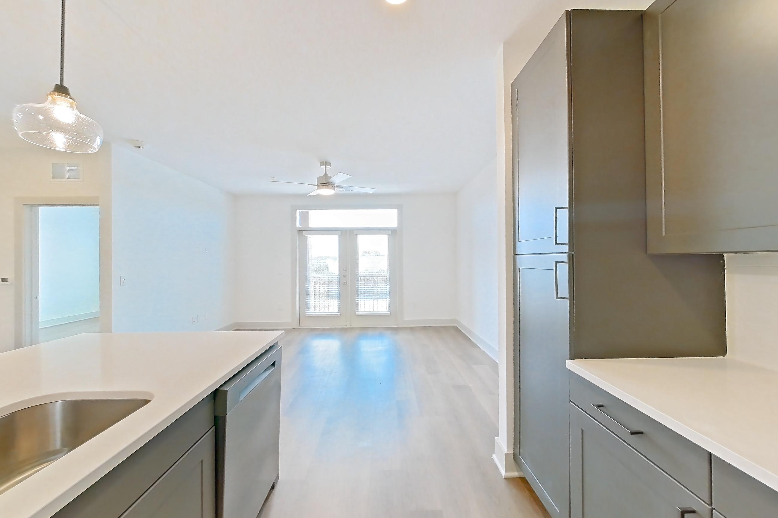 Kitchen with dishwasher, electric range, light countertops, light stone countertops, light wood-finish flooring, microwave, oven/range, and stainless steel appliances, Apartment 2206 at Groves South Congress