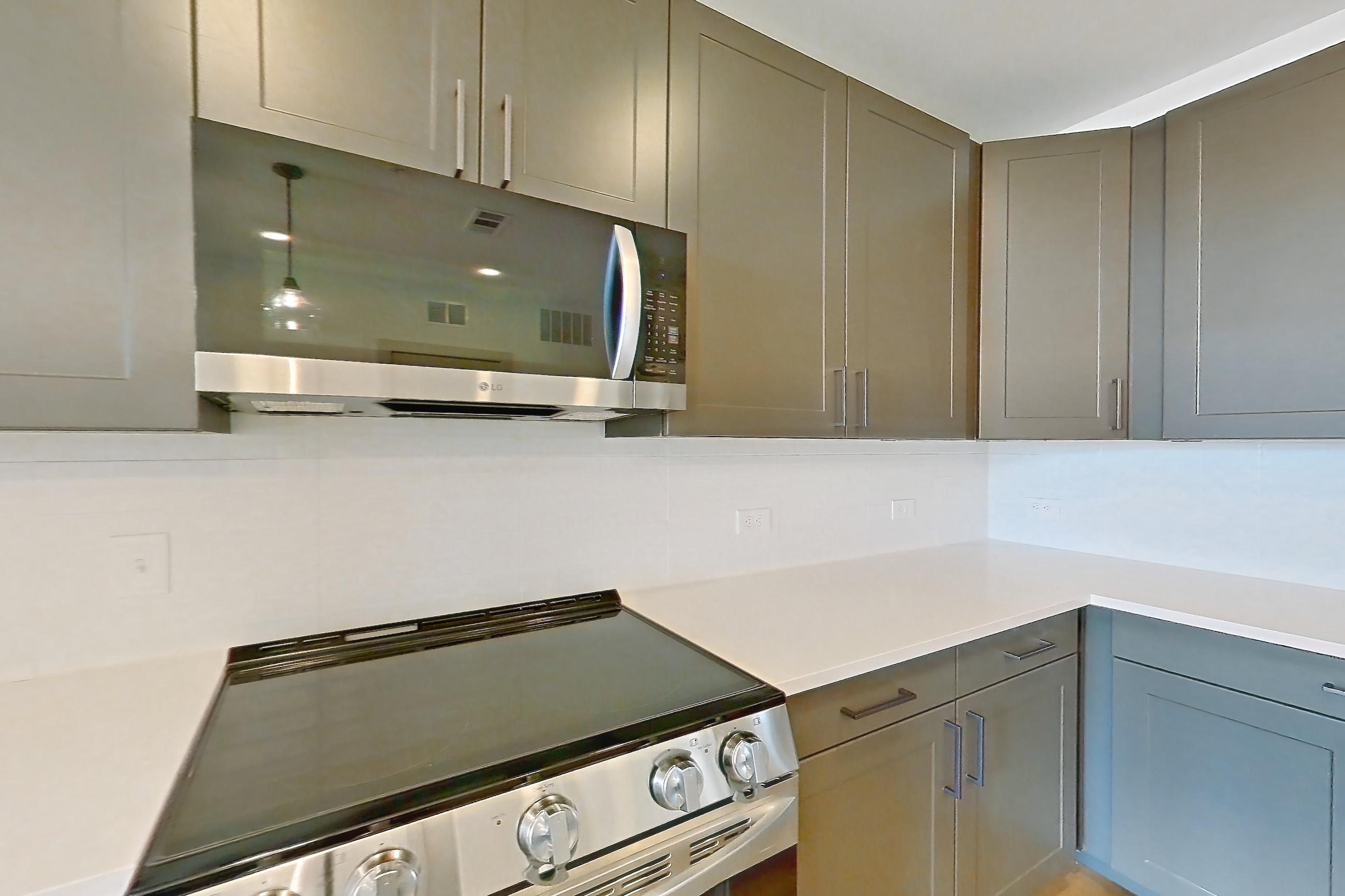 Kitchen with dishwasher, electric range, light countertops, light stone countertops, light wood-finish flooring, microwave, oven/range, and stainless steel appliances, Apartment 2206 at Groves South Congress