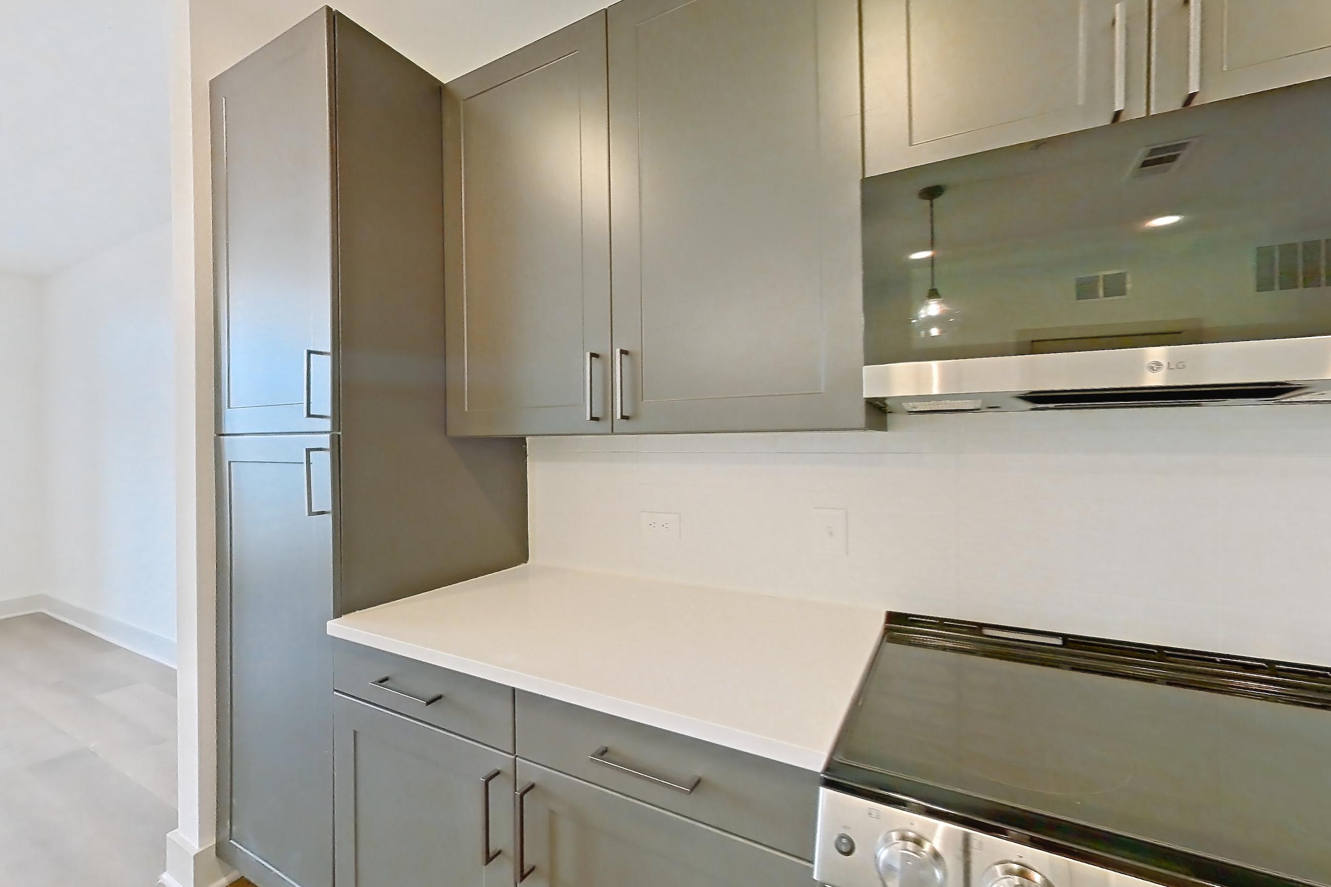 Kitchen with dishwasher, electric range, light countertops, light stone countertops, light wood-finish flooring, microwave, oven/range, and stainless steel appliances, Apartment 2206 at Groves South Congress