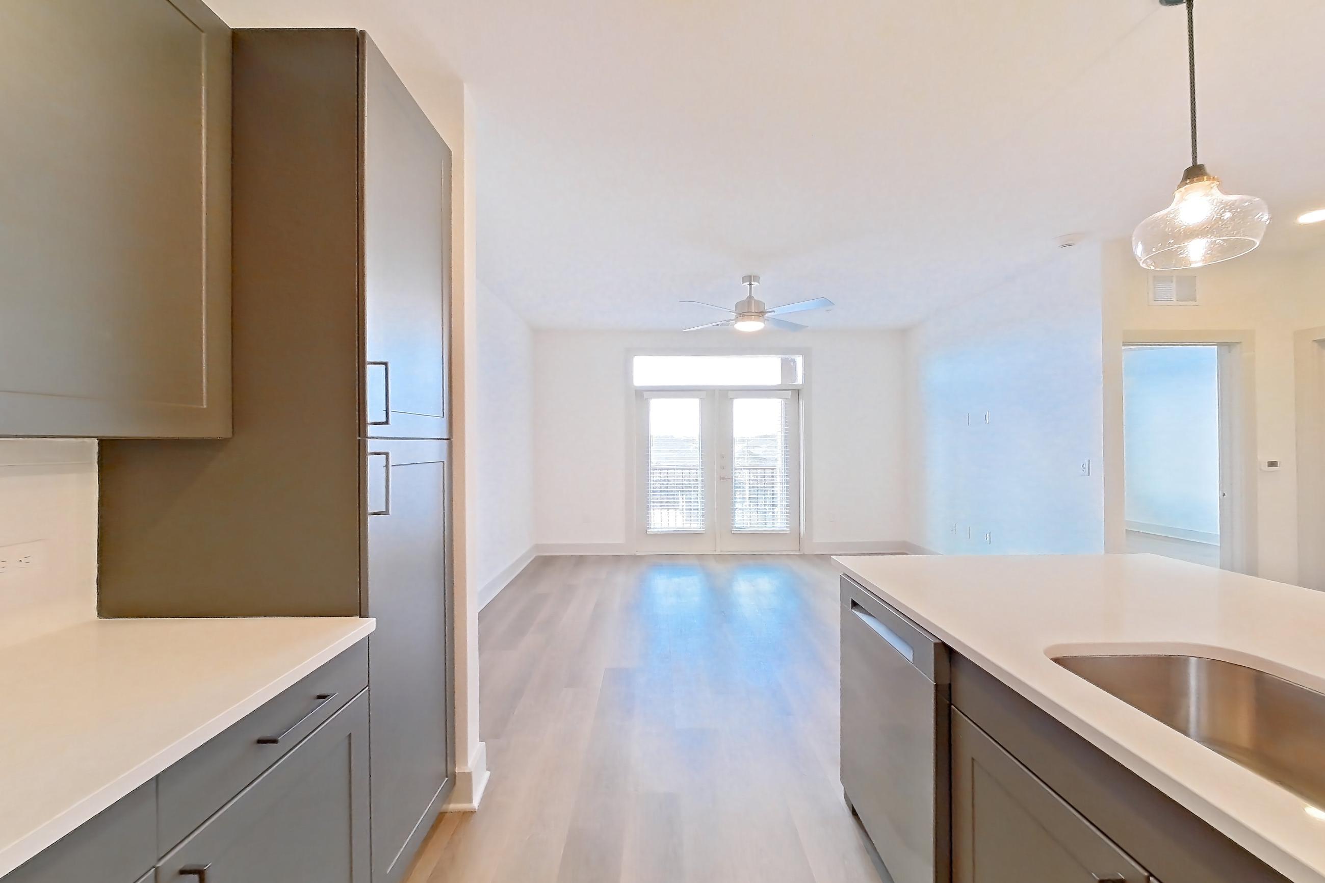 Kitchen with dishwasher, electric range, light countertops, light stone countertops, light wood-finish flooring, microwave, oven/range, and stainless steel appliances, Apartment 2208 at Groves South Congress