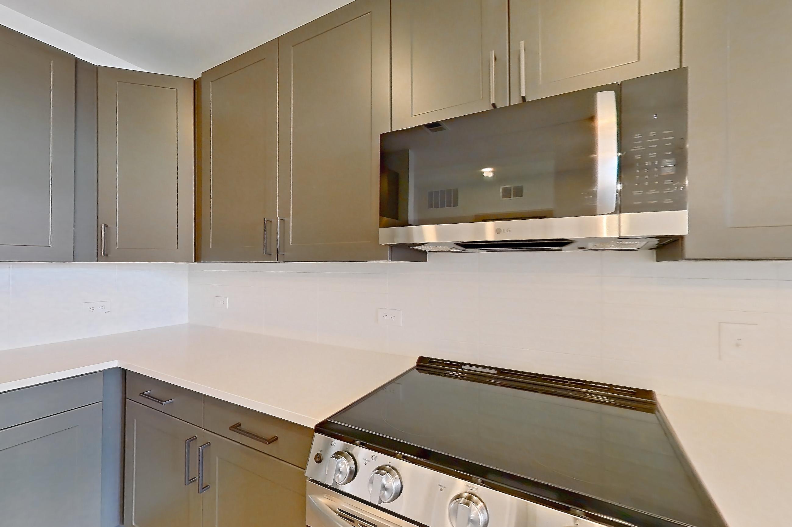 Kitchen with dishwasher, electric range, light countertops, light stone countertops, light wood-finish flooring, microwave, oven/range, and stainless steel appliances, Apartment 2208 at Groves South Congress